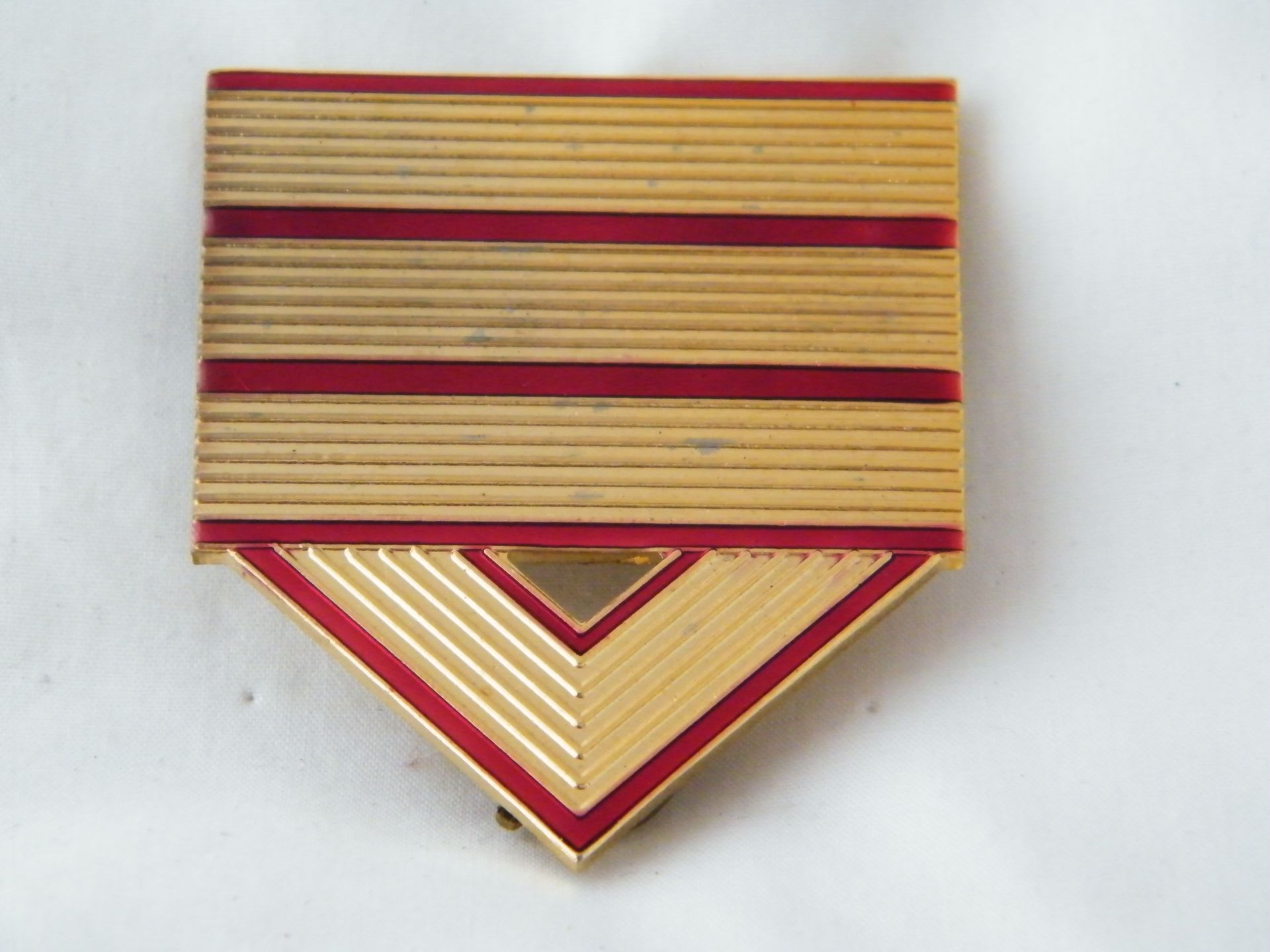 Una insignia dorada y roja con un triángulo en el medio