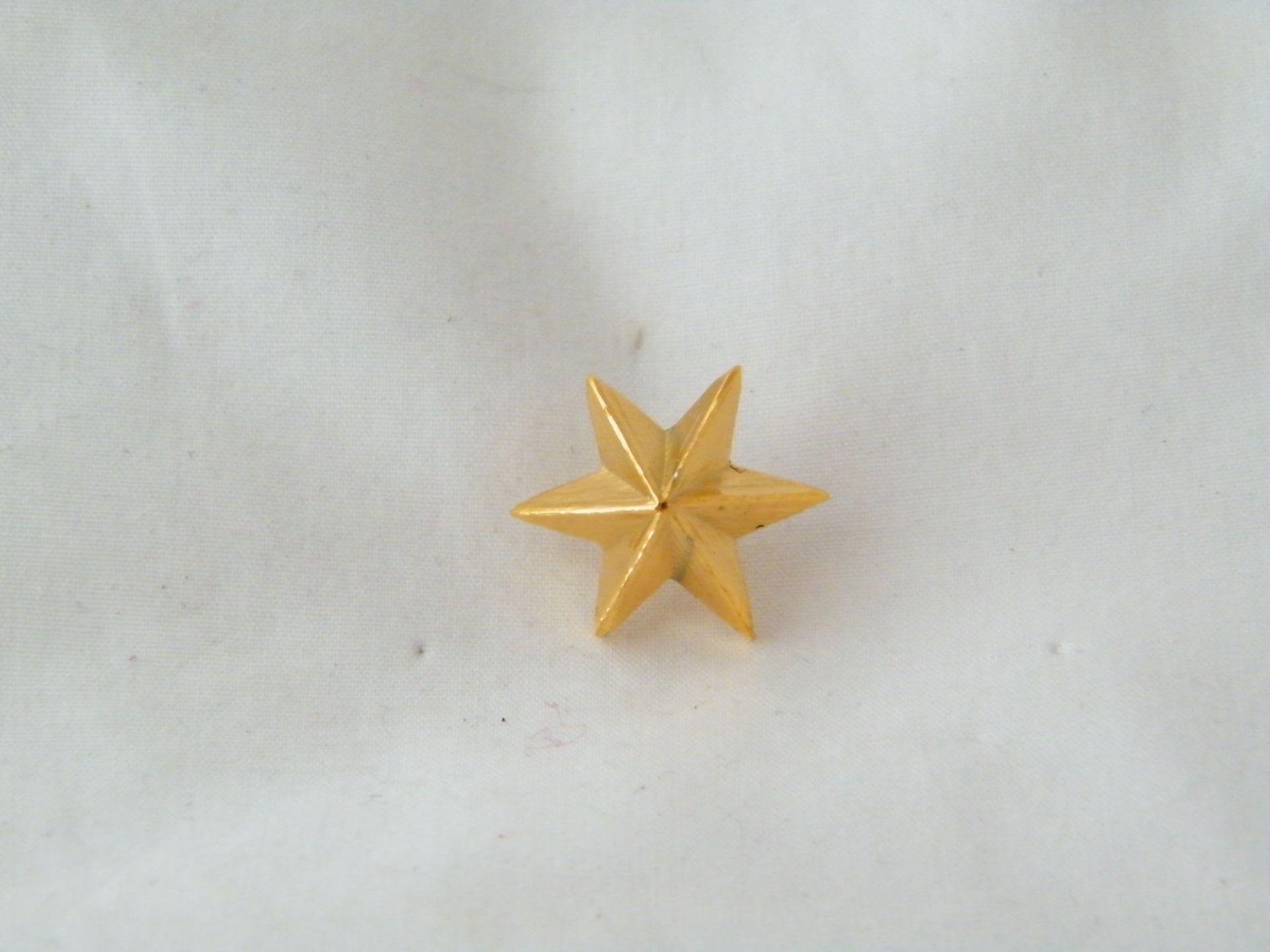 Una pequeña estrella dorada está sentada sobre una superficie blanca.