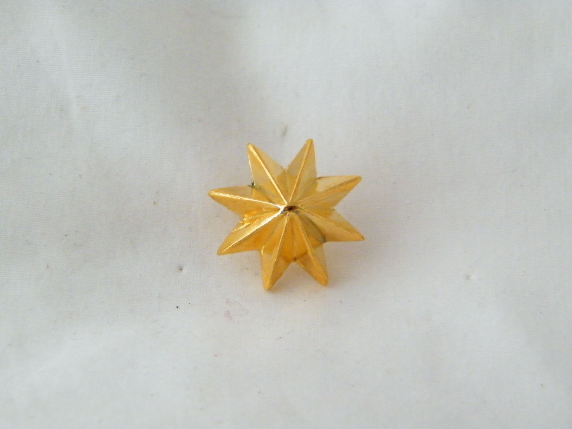 Una estrella dorada con un agujero en el medio está sobre una superficie blanca.