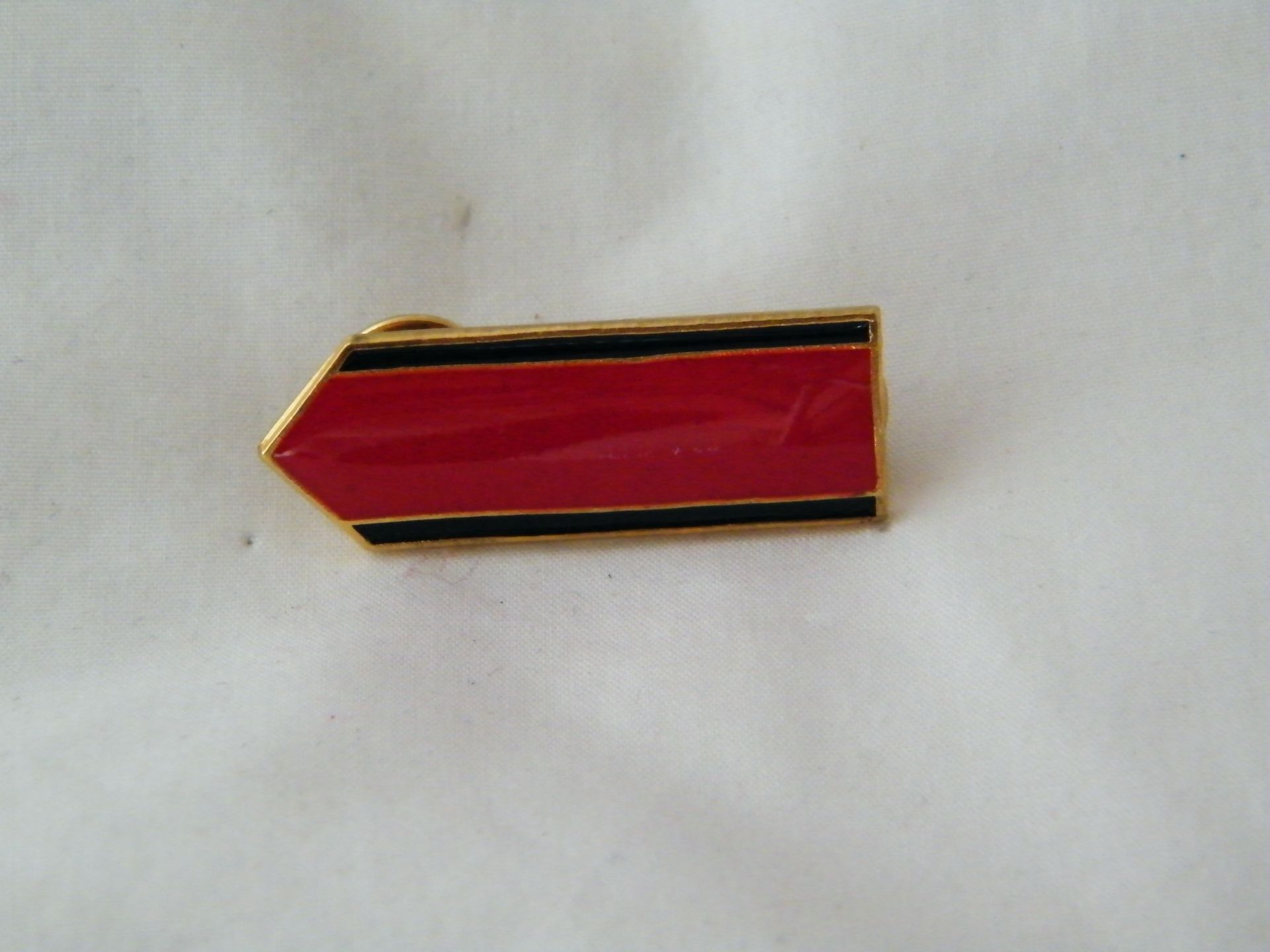 Un alfiler de flecha roja con rayas negras sobre una superficie blanca