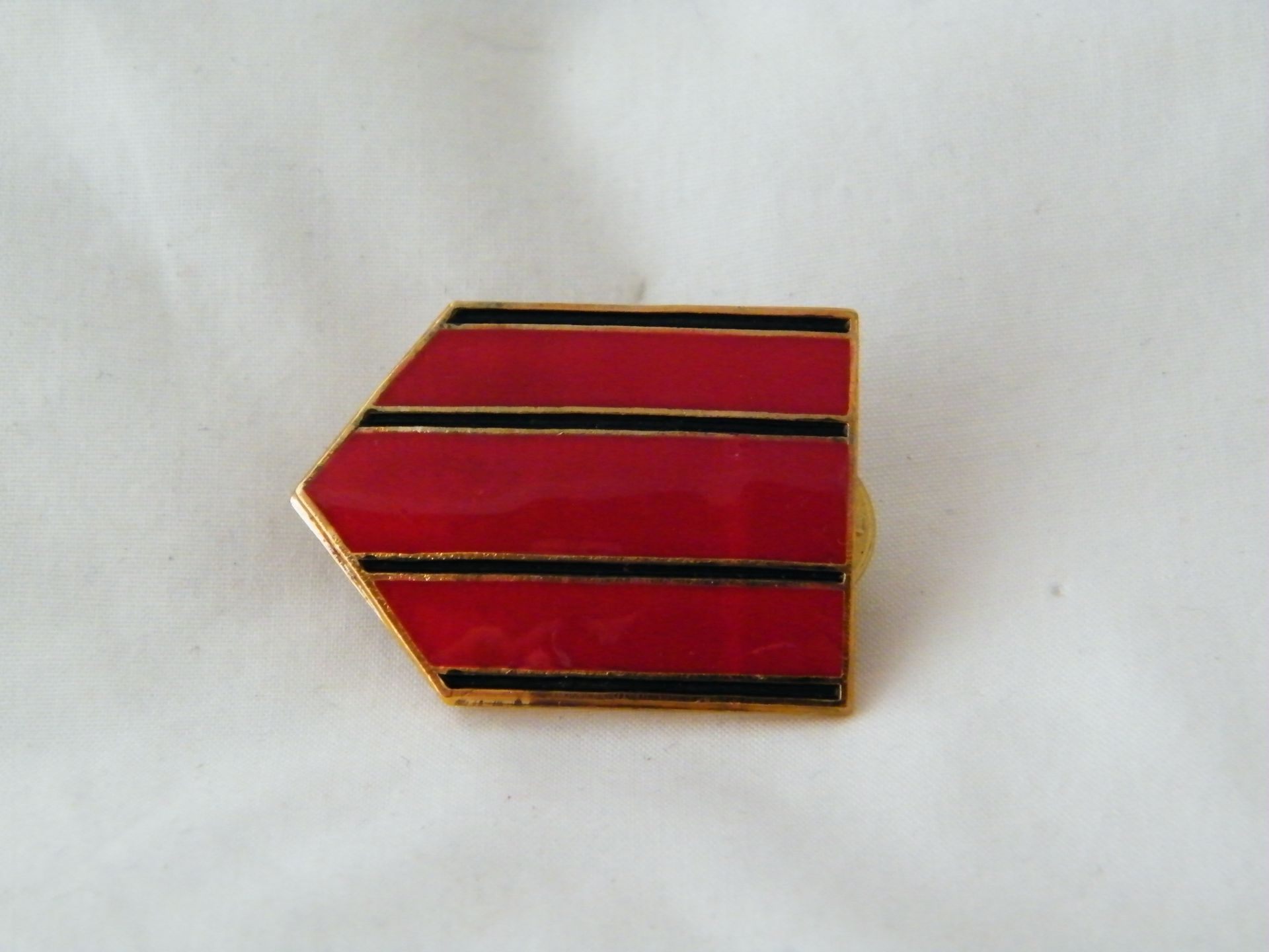 Un alfiler rojo con rayas negras está sobre una superficie blanca