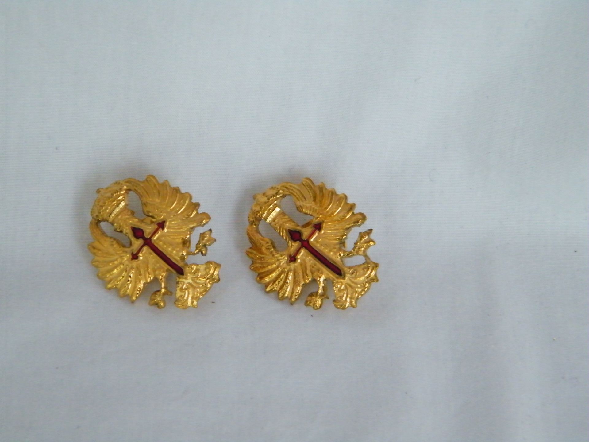 Un par de pendientes de oro con una cruz en ellos.