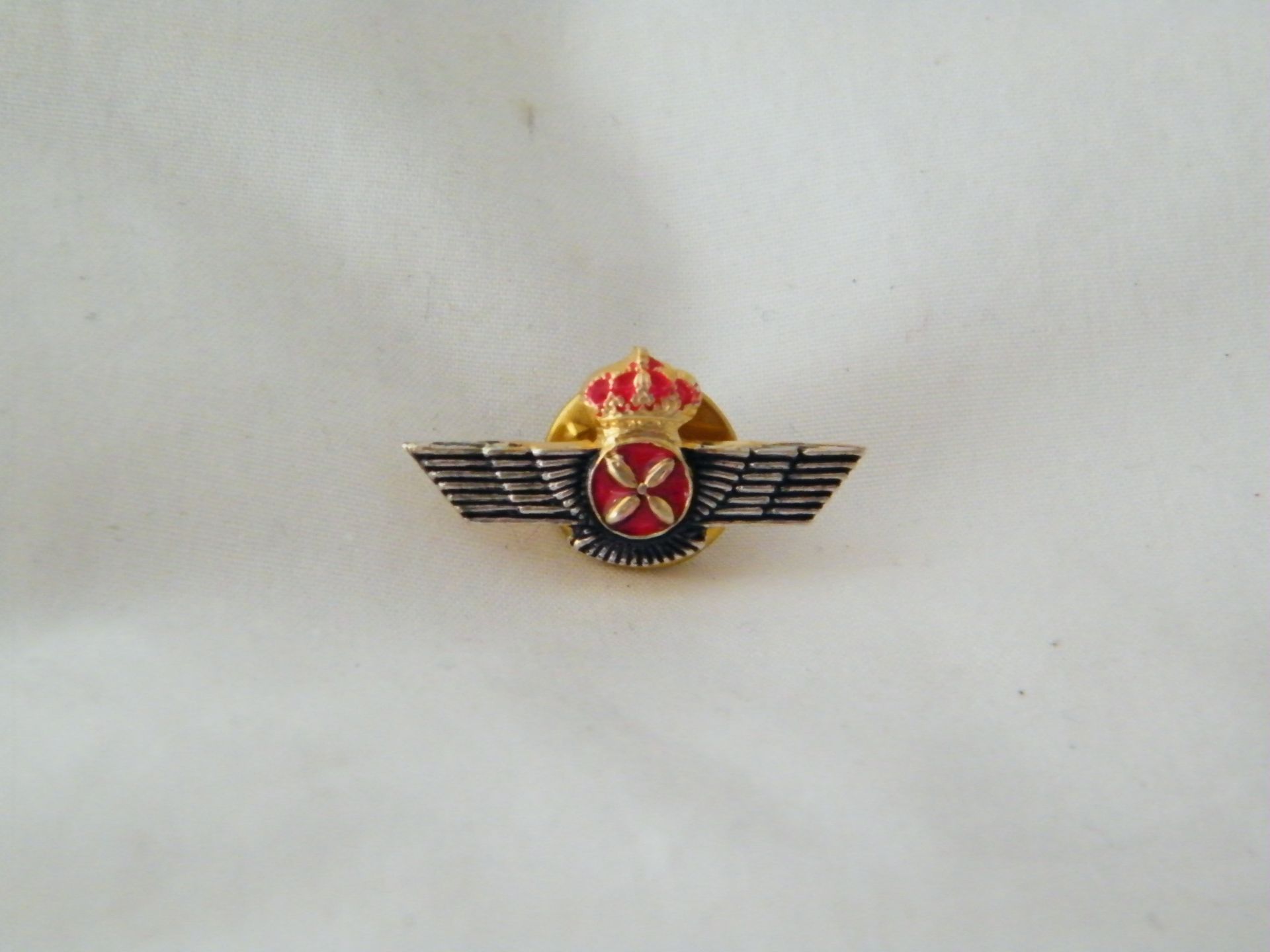 Un alfiler con alas y una cruz en él.