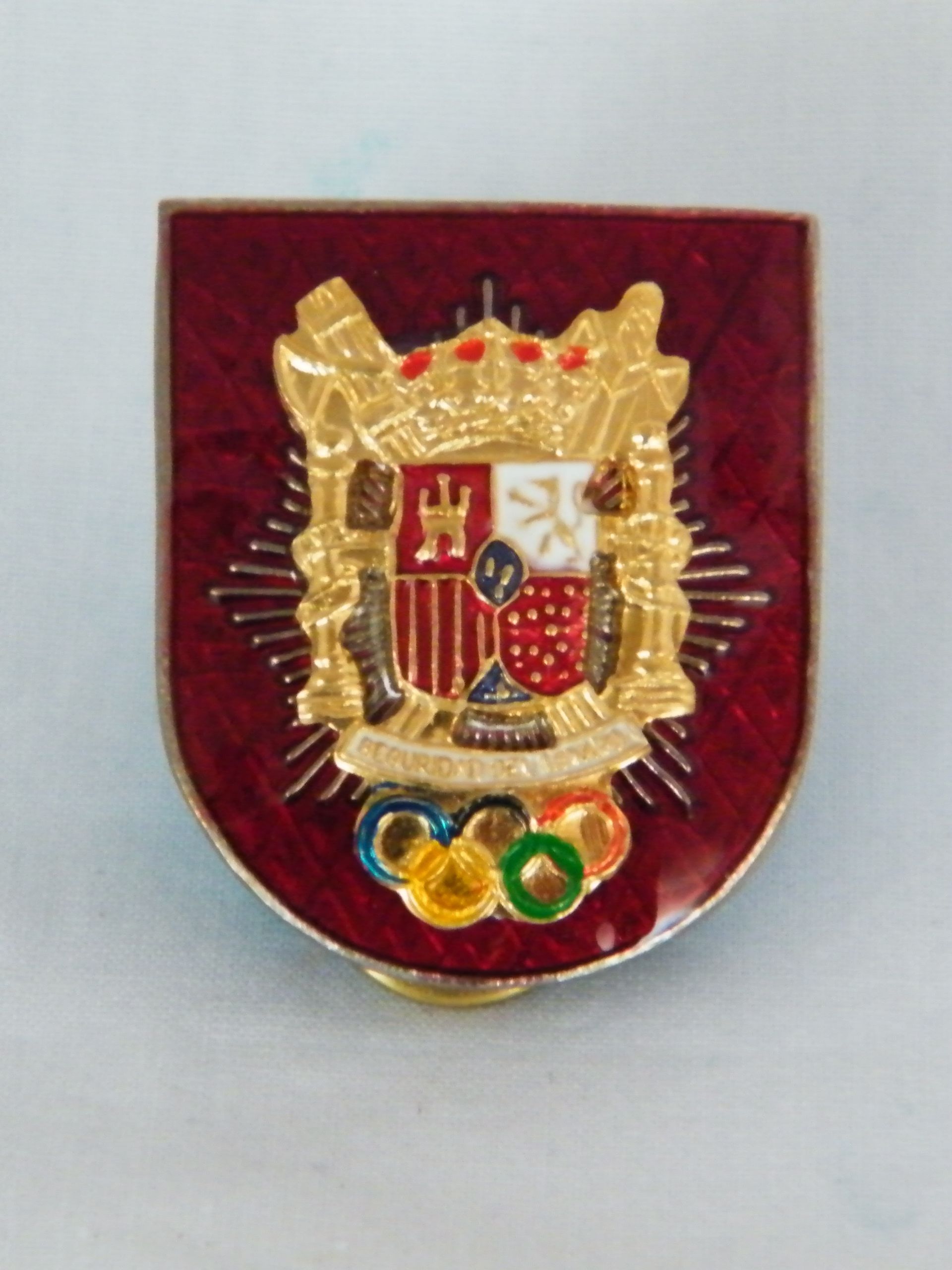 Una insignia con un escudo de armas y anillos olímpicos.