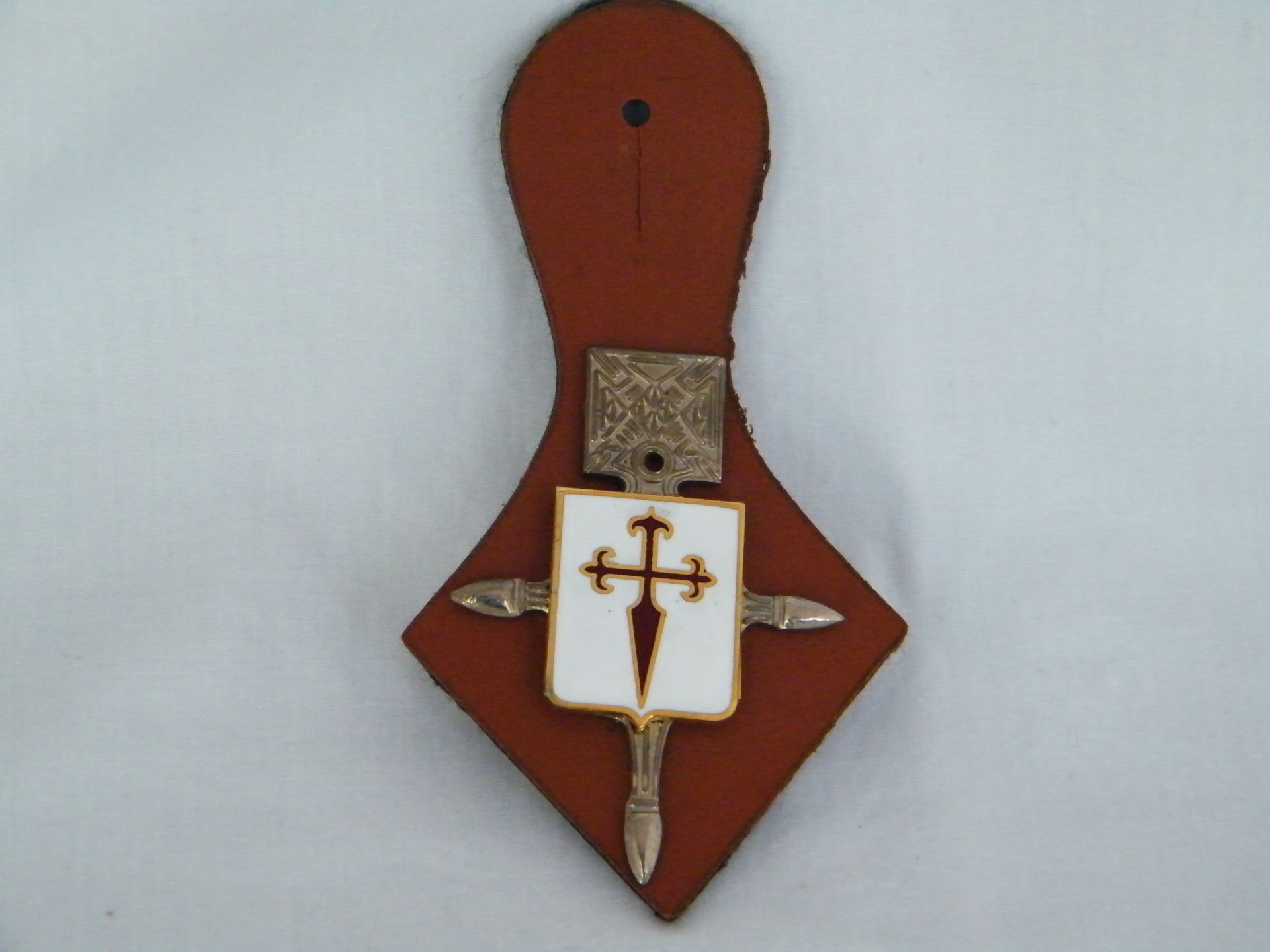Una insignia marrón con una cruz blanca.