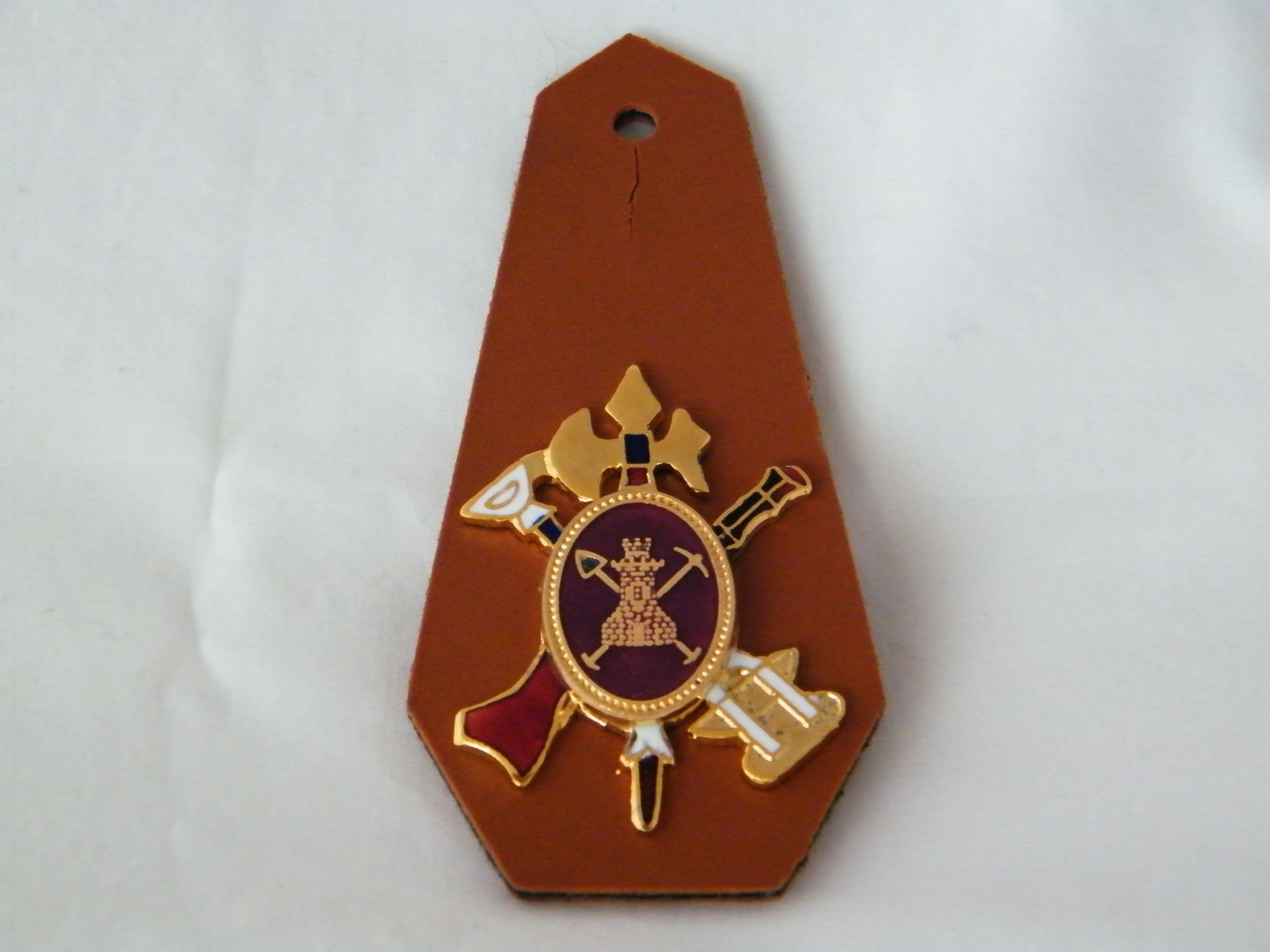 Una charretera marrón con un emblema dorado.