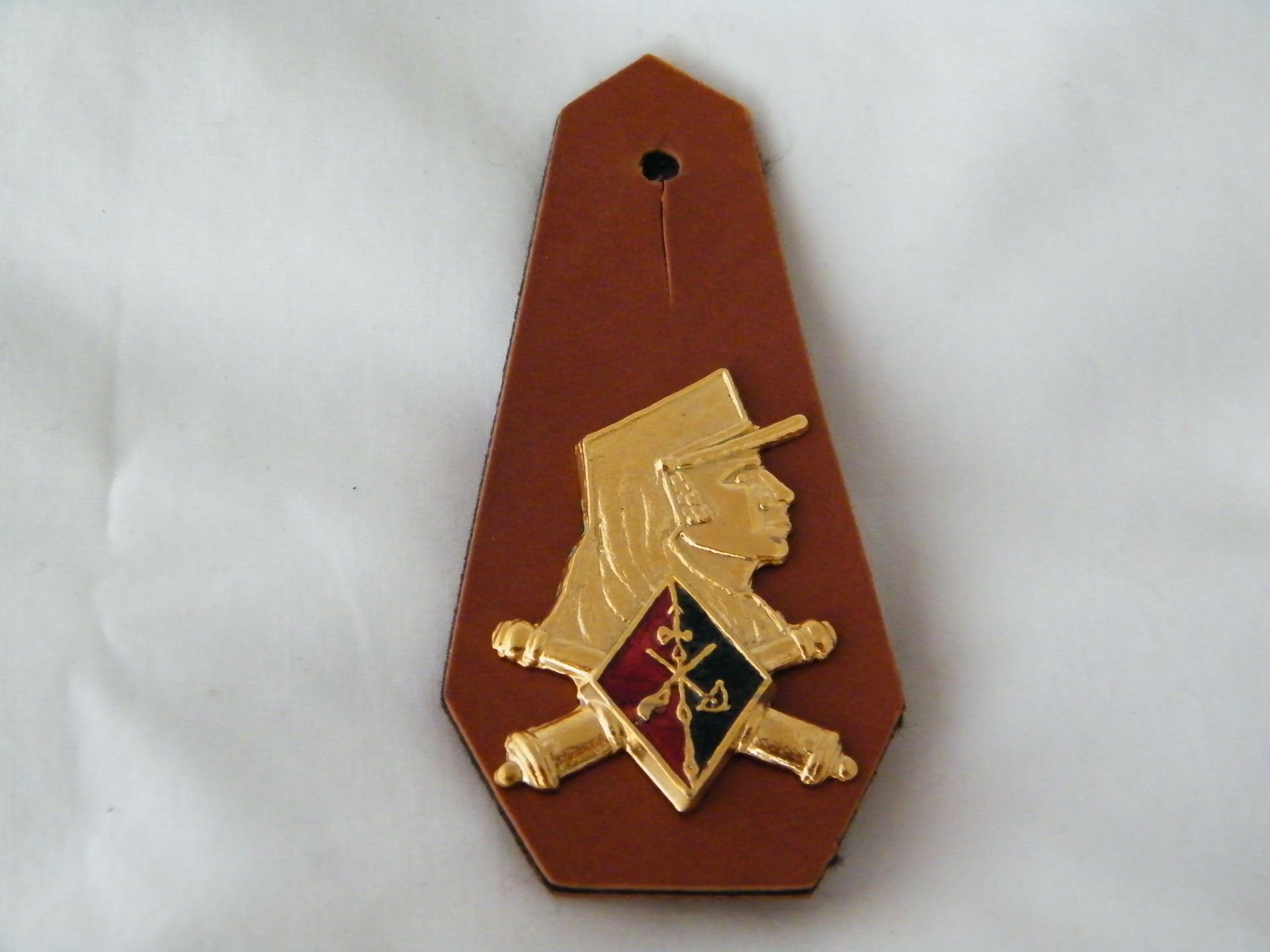 Una insignia marrón con un soldado dorado en ella