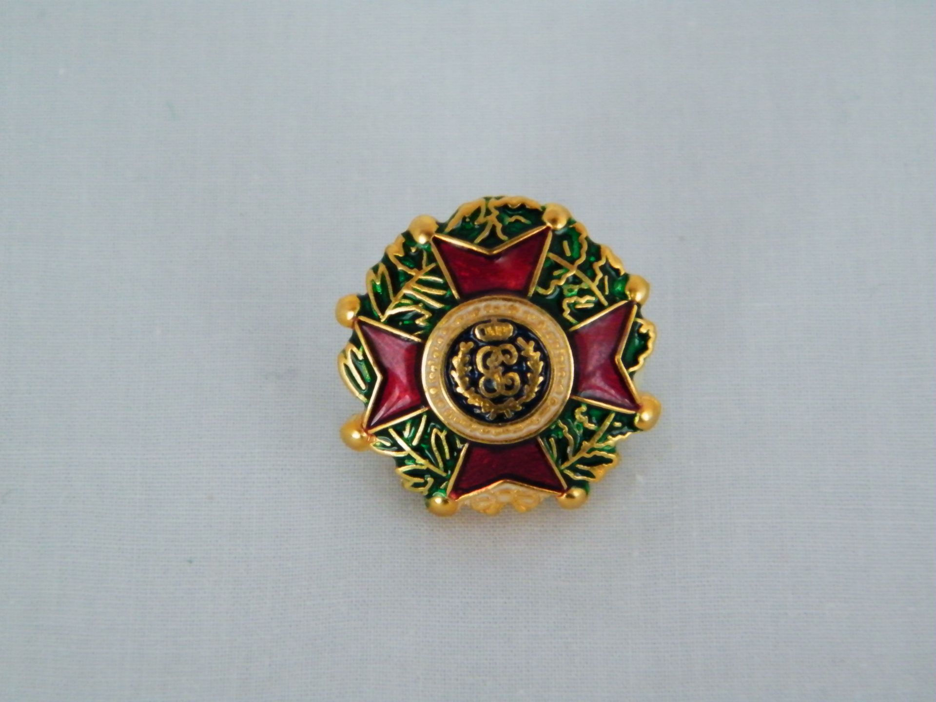 Una insignia dorada y roja con la letra g.