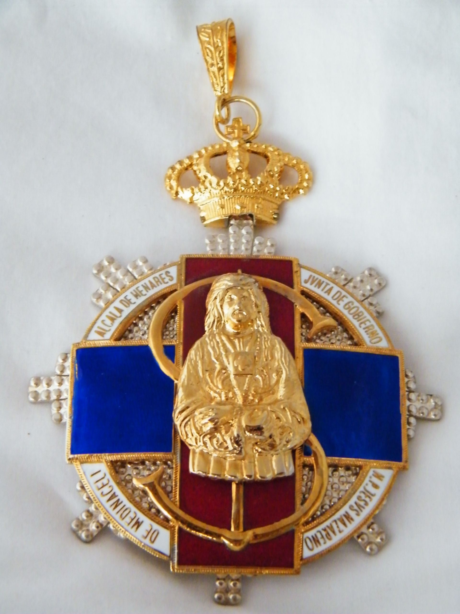 Una medalla de oro con una corona y Jesús en ella.