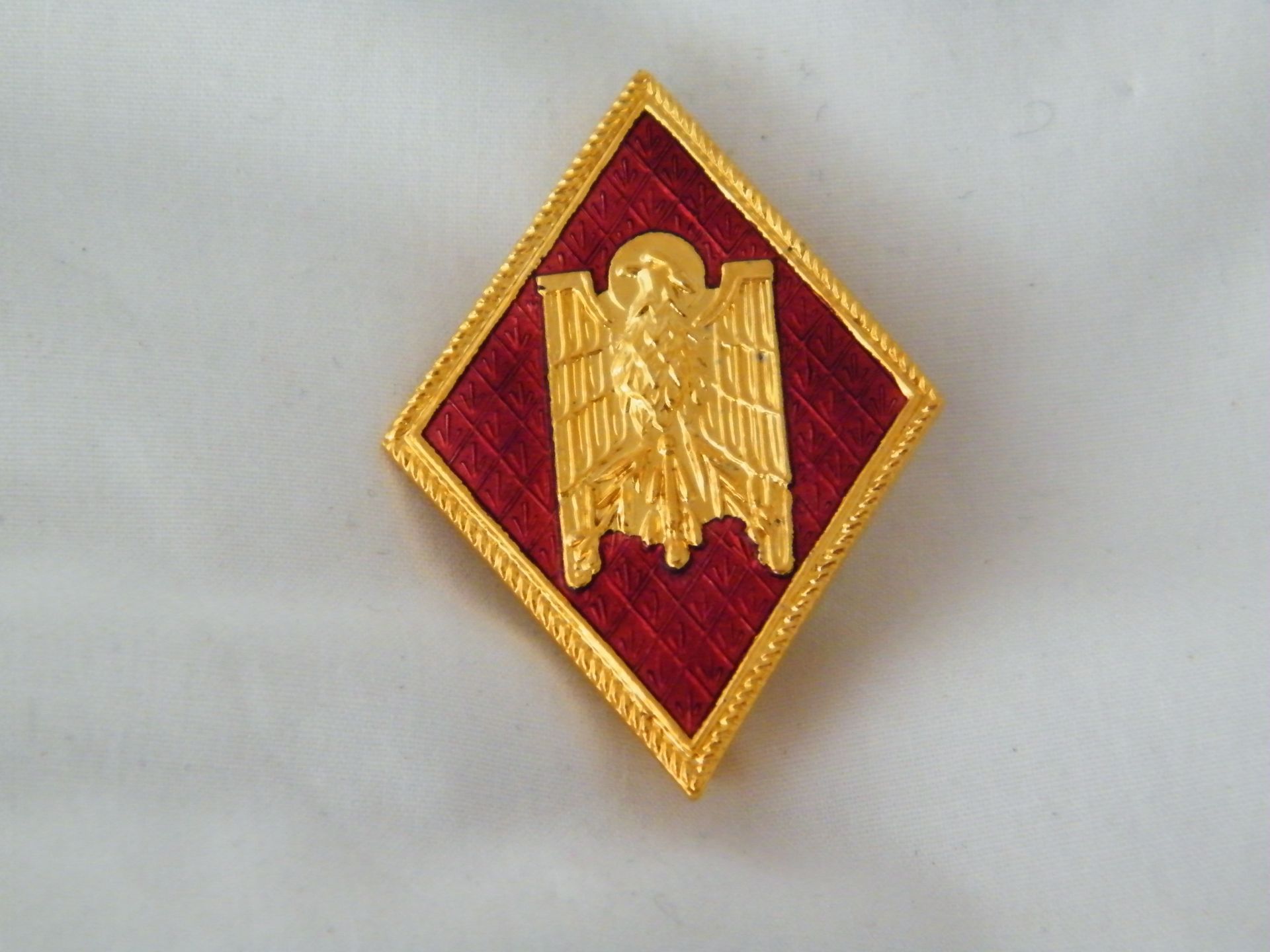 Una insignia dorada y roja con un águila.