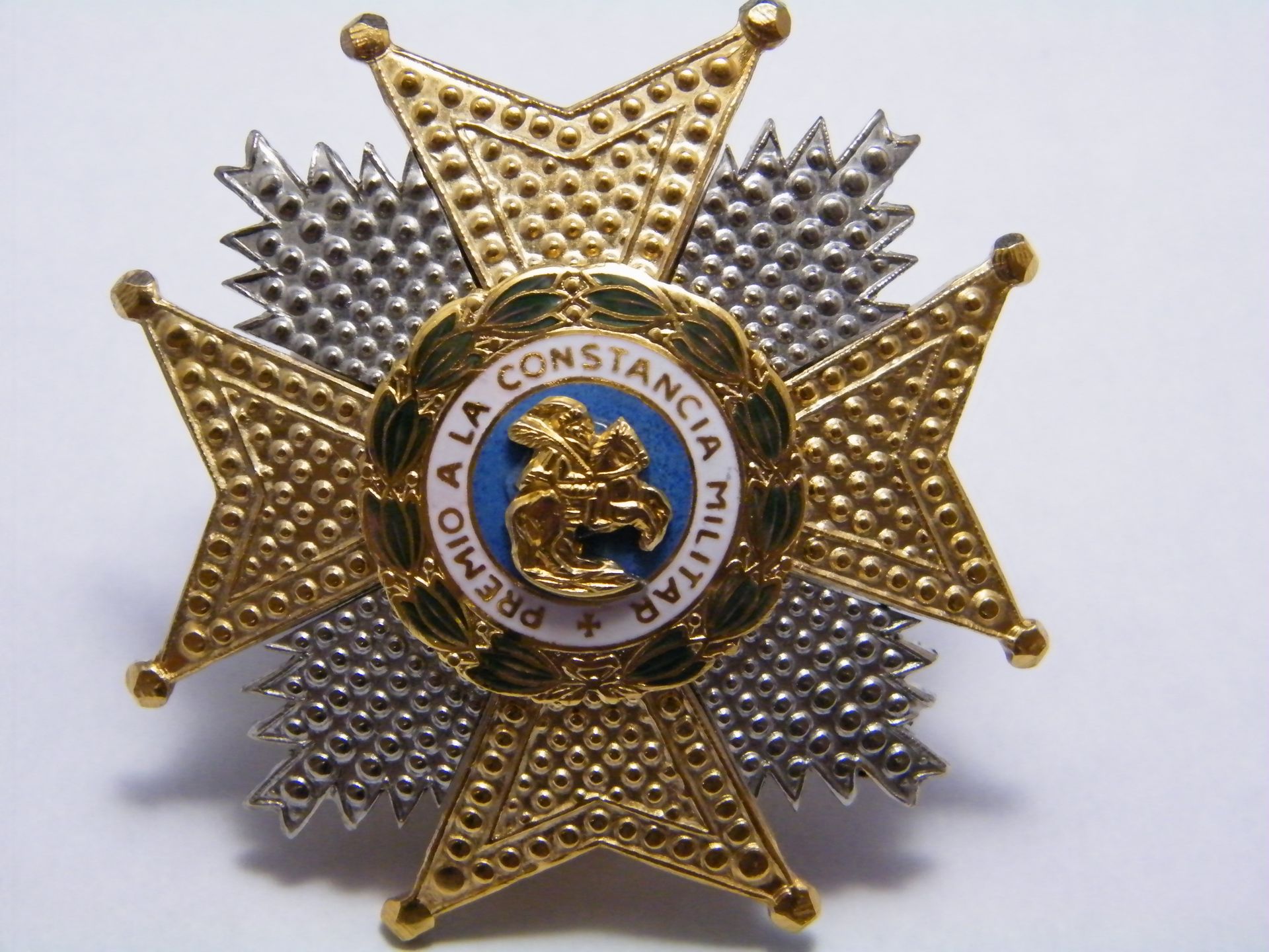 Una insignia de oro y plata que dice a la constancia militar