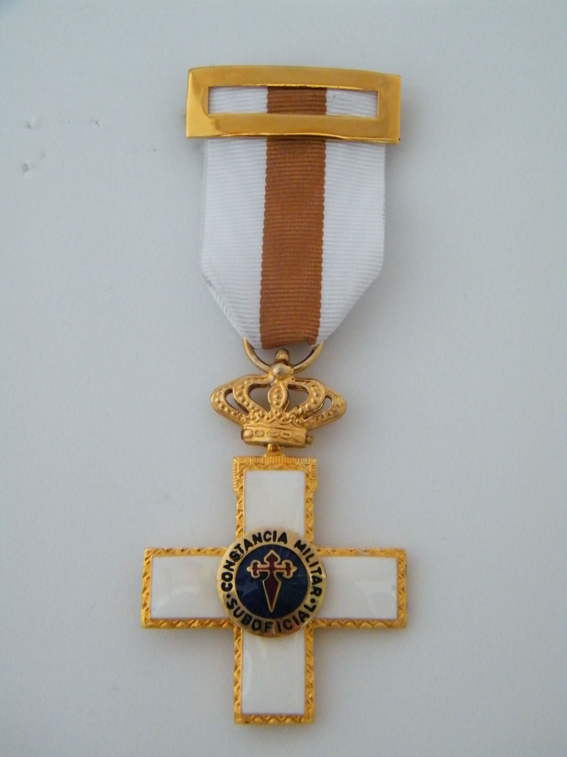 Una medalla de oro y blanco con una cruz en ella