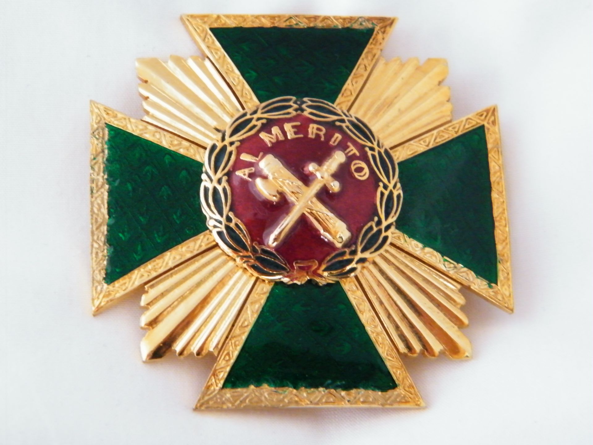 Una medalla verde y dorada con la palabra mérito en ella