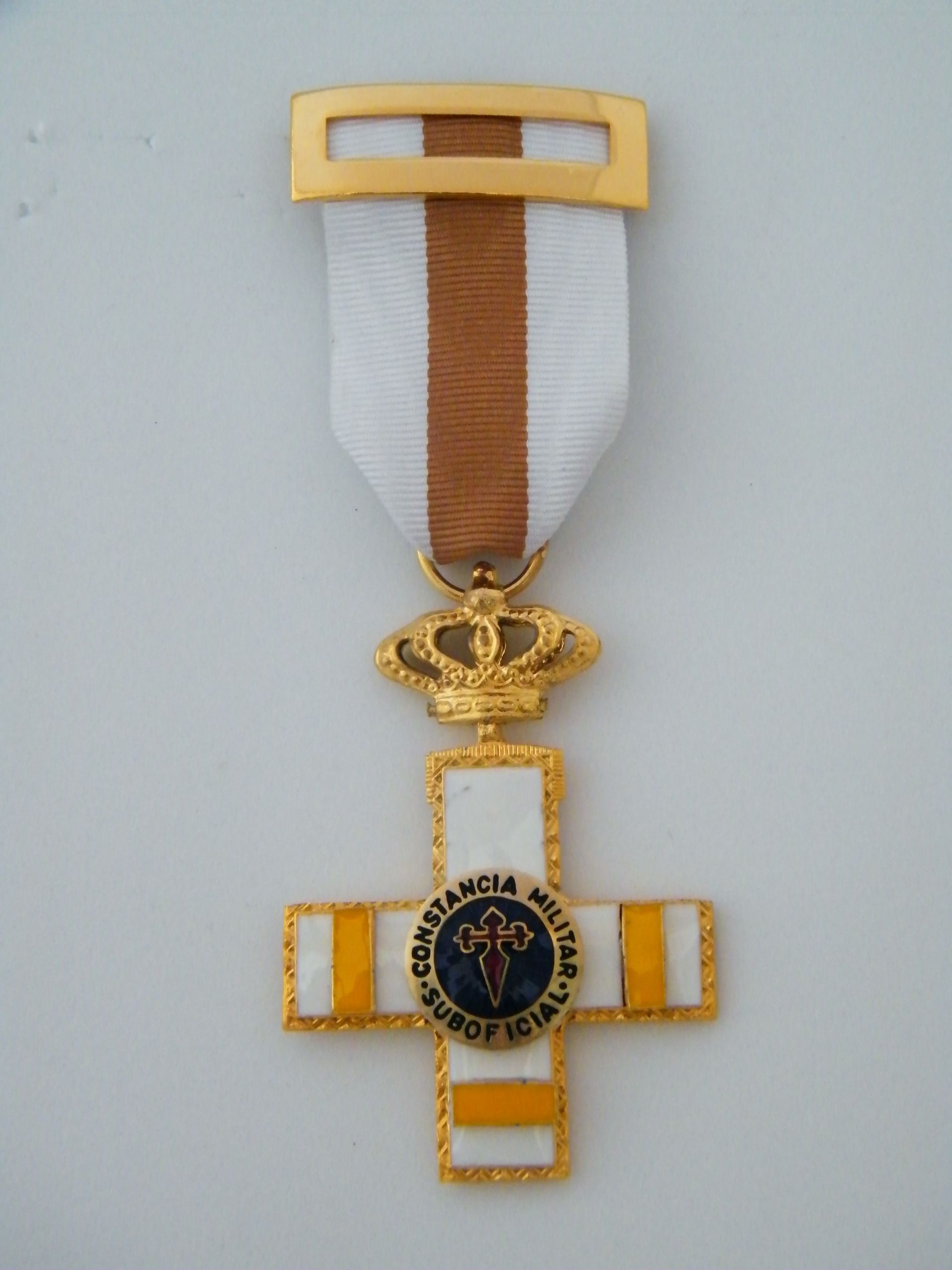 Una medalla de oro y blanco con una cruz y una corona.