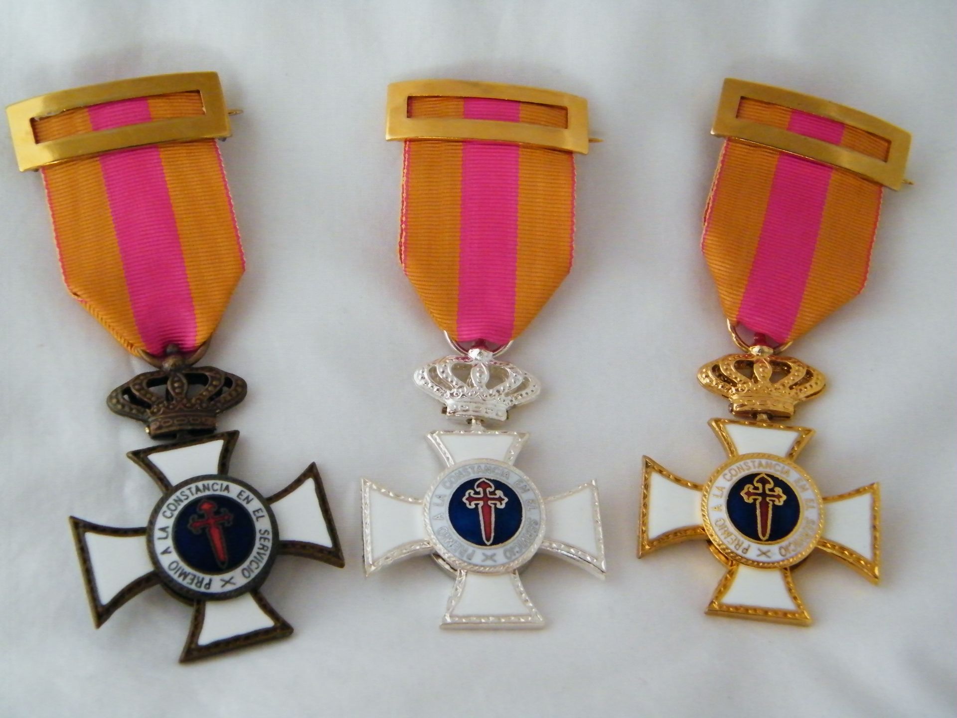 Tres medallas están alineadas sobre una superficie blanca