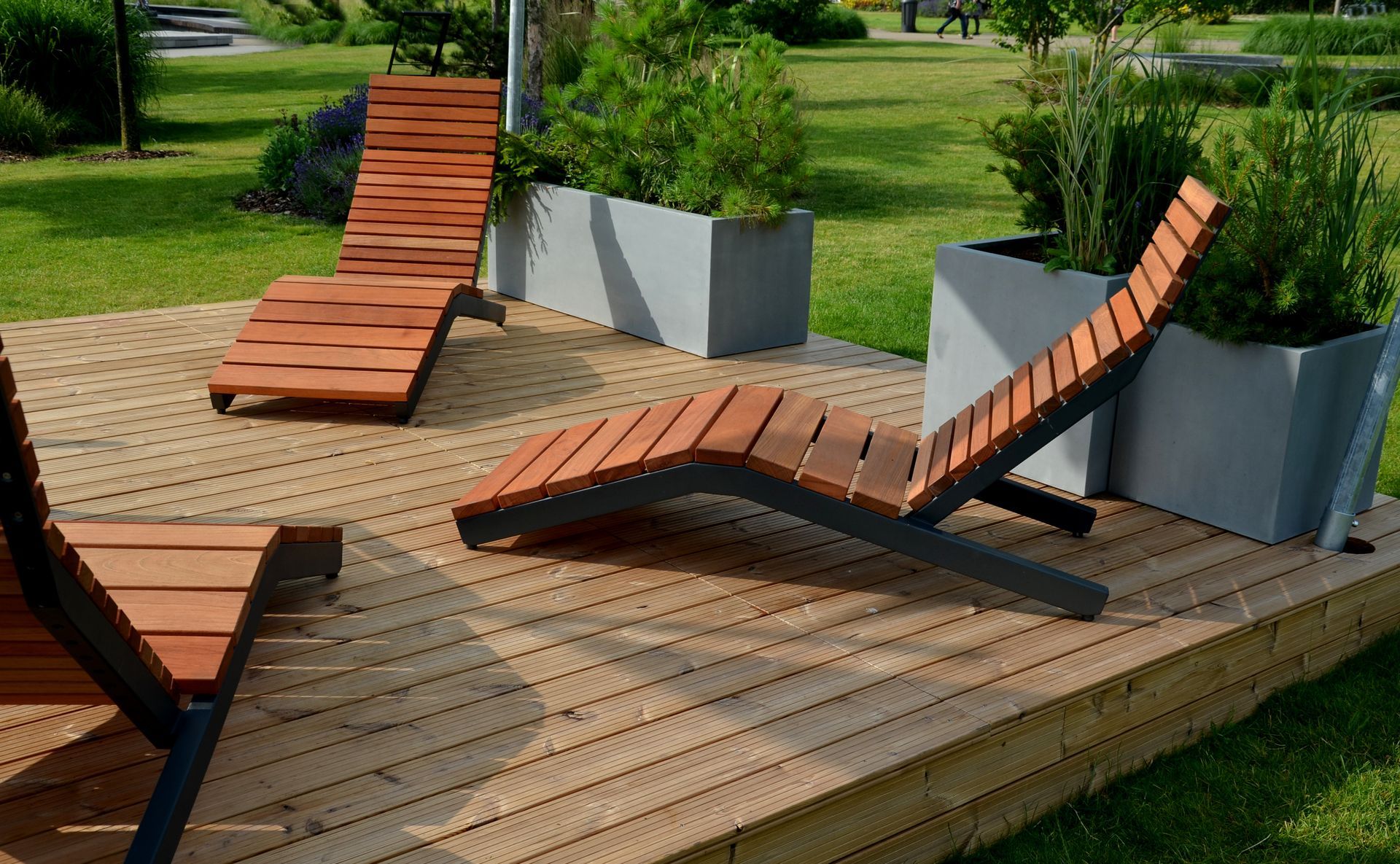Trois chaises longues modernes en bois sont installées sur une terrasse en bois.