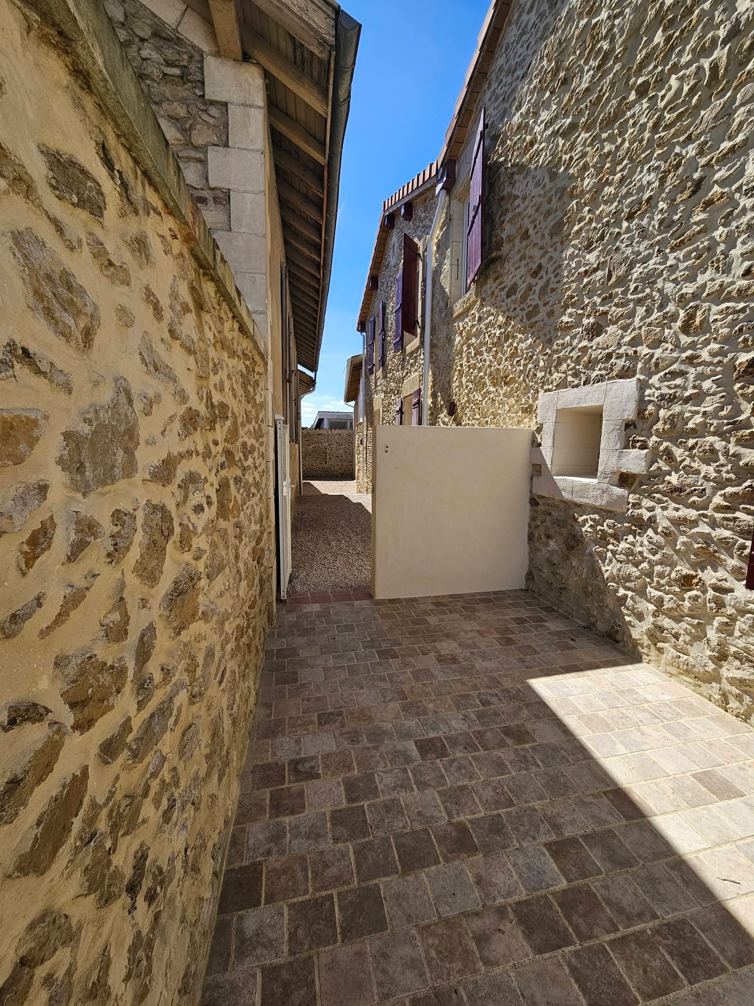 Un étroit chemin de pierre entre deux bâtiments rustiques en pierre.