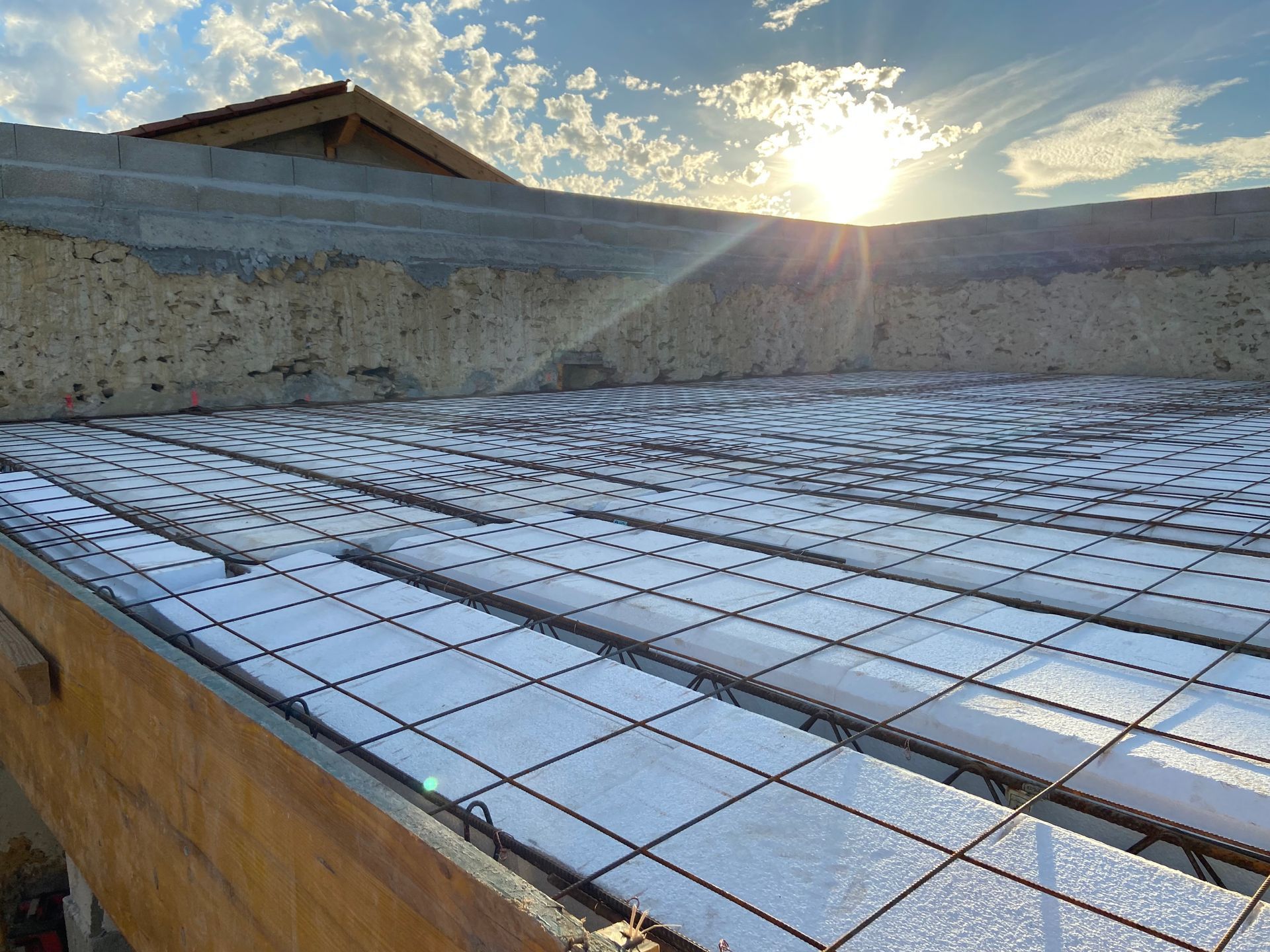 Chantier de construction montrant un treillis d'armature en acier posé sur des blocs d'isolation en mousse.