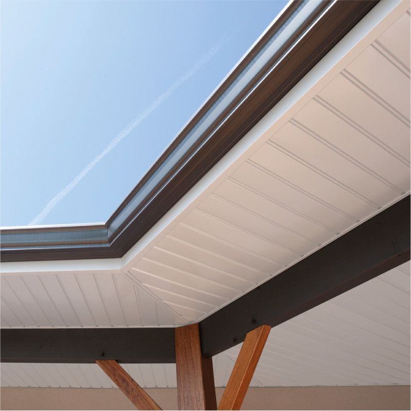 Une poutre de soutien en bois soutient un plafond blanc nervuré sous une corniche de toit en métal sombre.