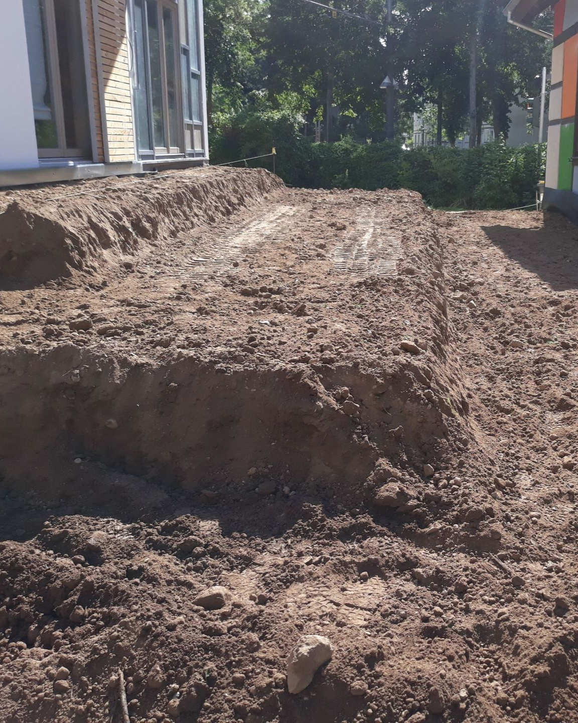 Chargeuse de construction jaune sur un terrain en terre, défrichant le terrain avec un ciel bleu en arrière-plan.