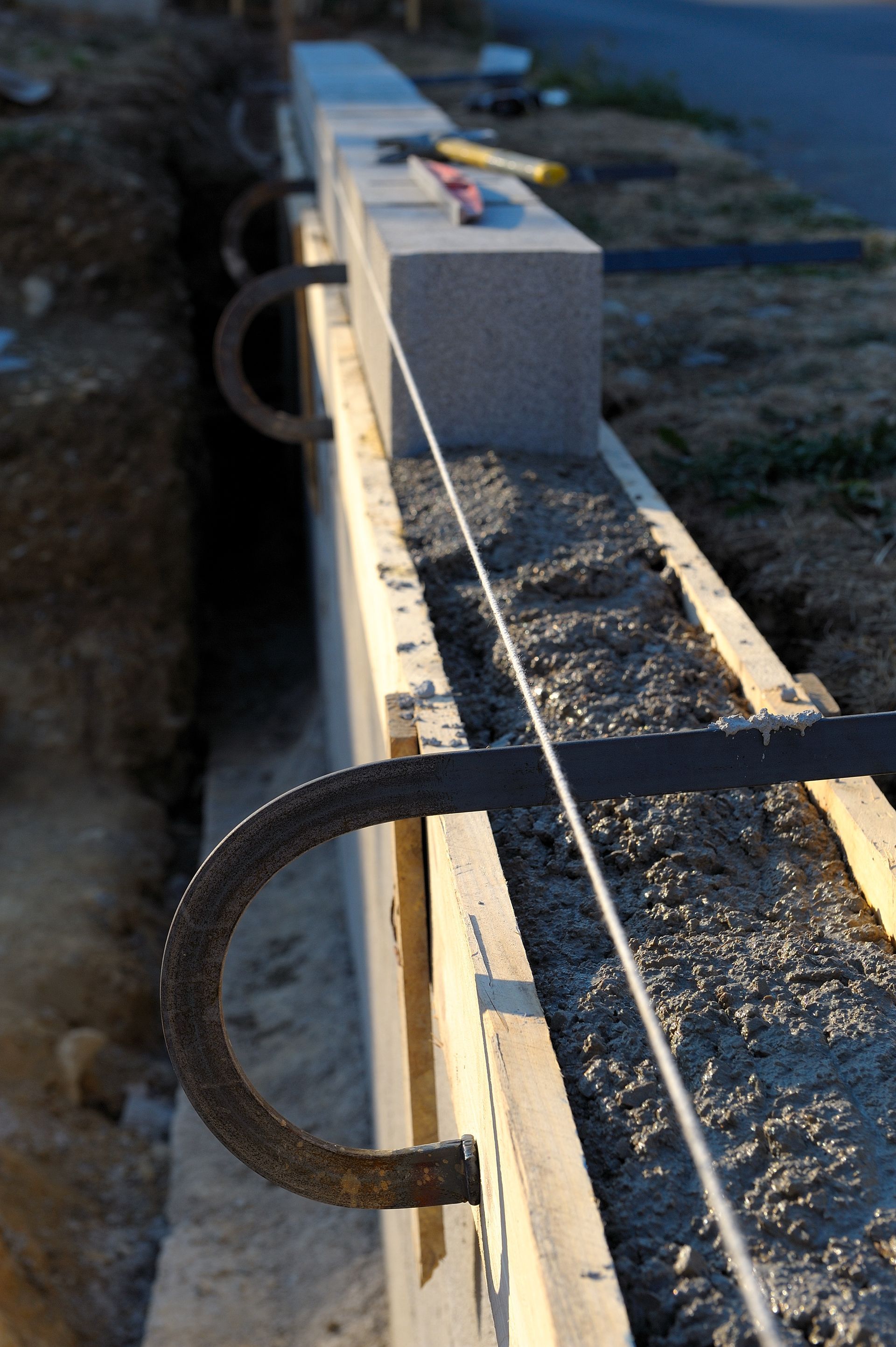 Construction d'un muret : coffrage en bois avec béton, fers à béton et cordelette.