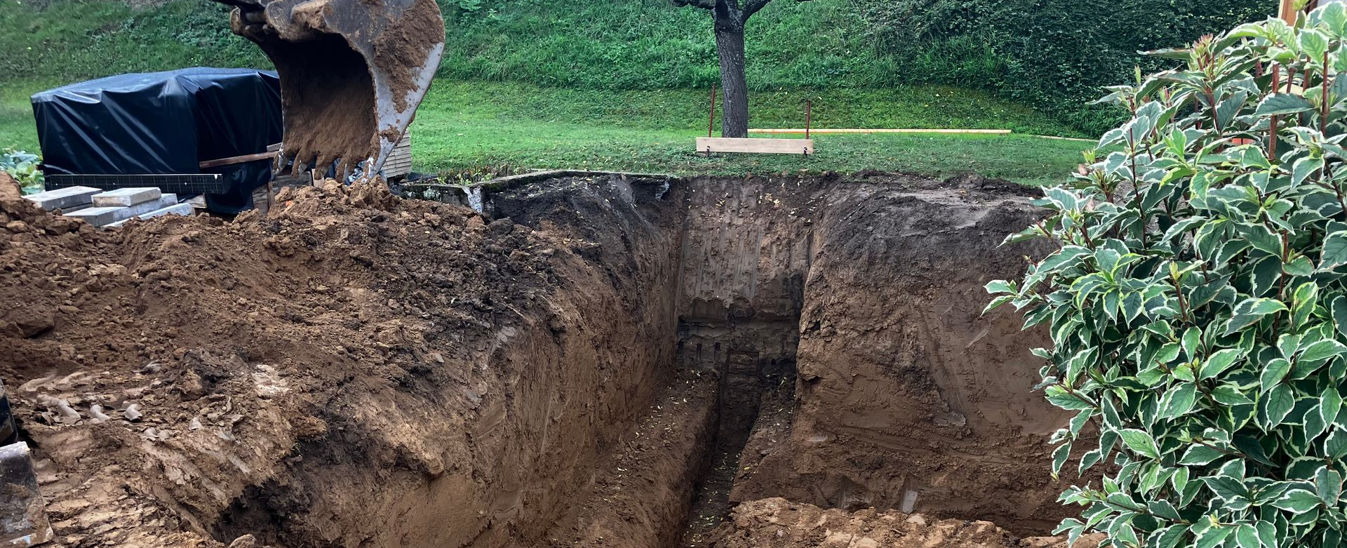 Tuyaux en béton empilés sur la terre avec de l'herbe verte en arrière-plan.