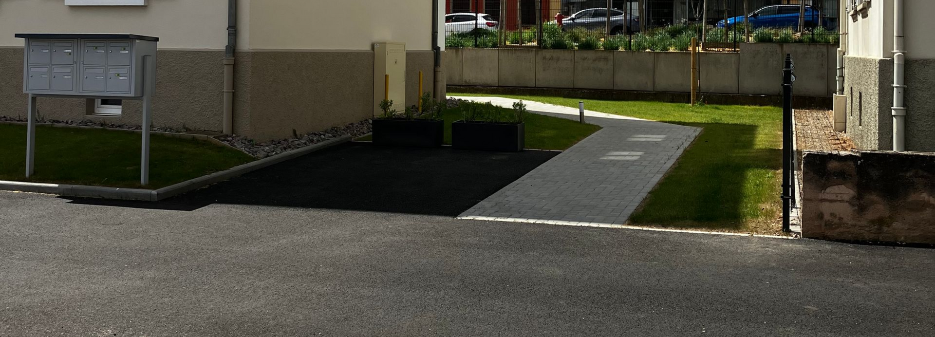 Stationnement avec lignes de places de stationnement peintes en blanc sur une surface asphaltée gris foncé.