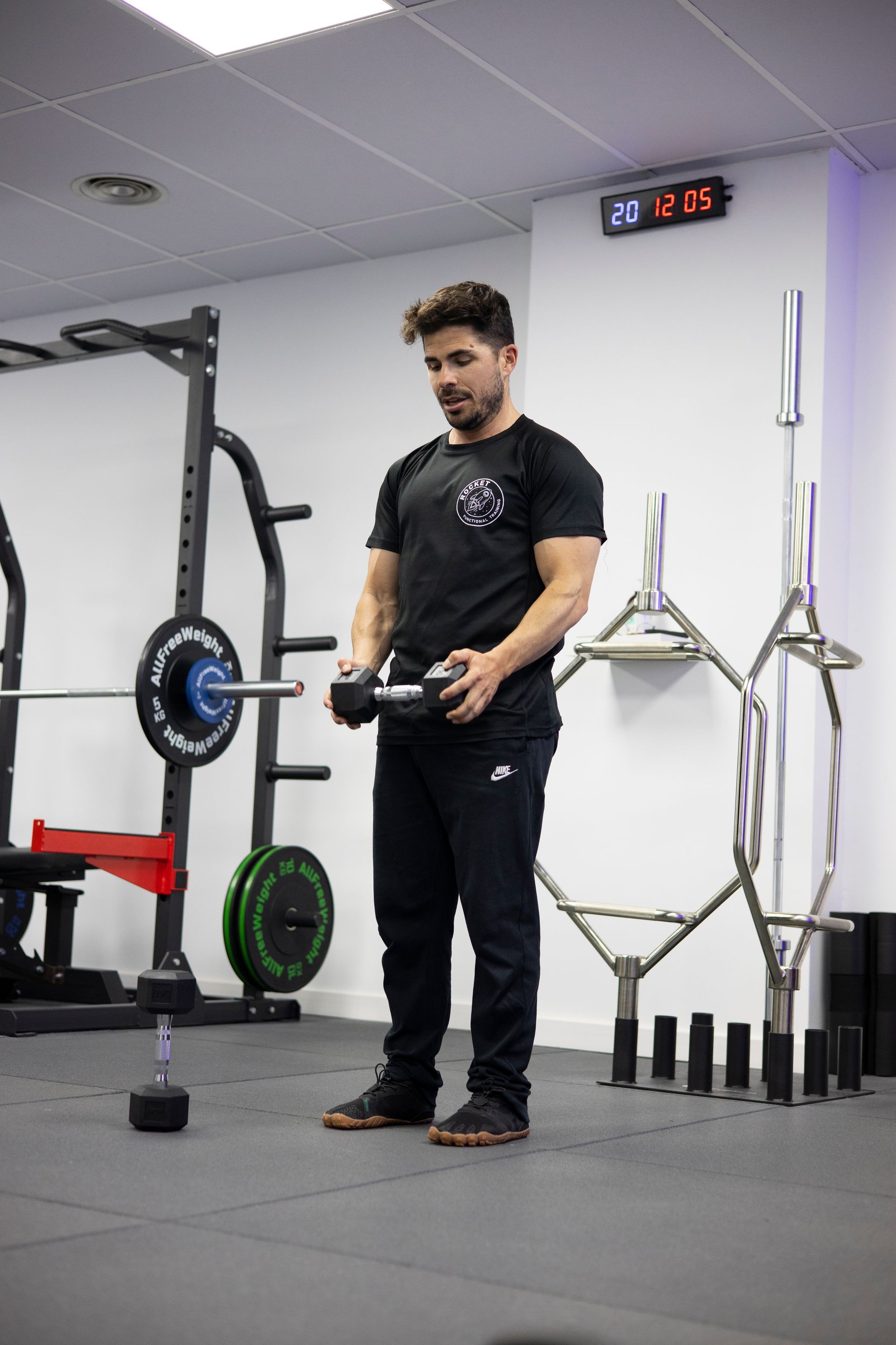 Un hombre sostiene una barra en un gimnasio.
