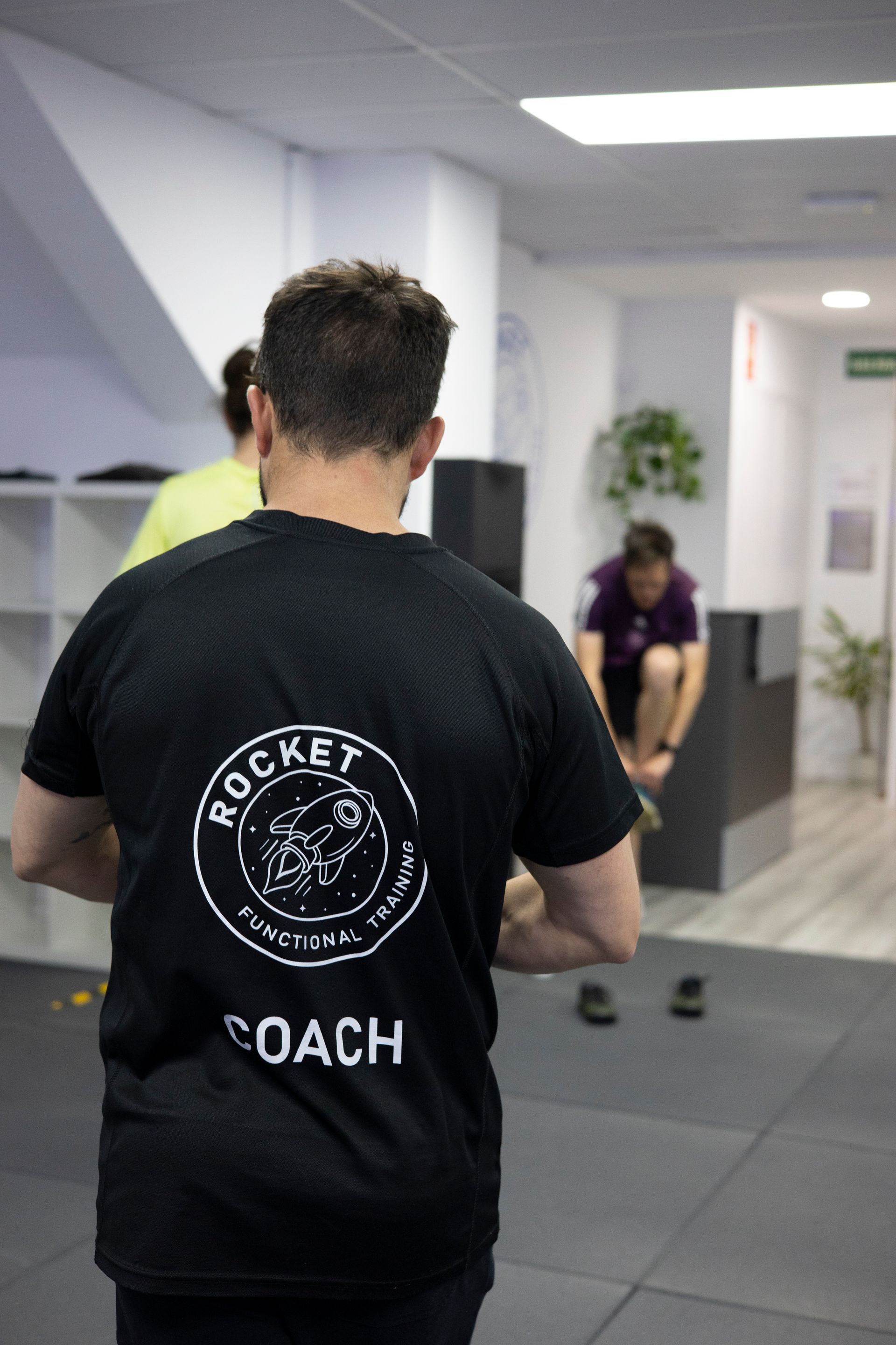Un hombre que llevaba una camisa negra con la palabra entrenador escrita en ella.