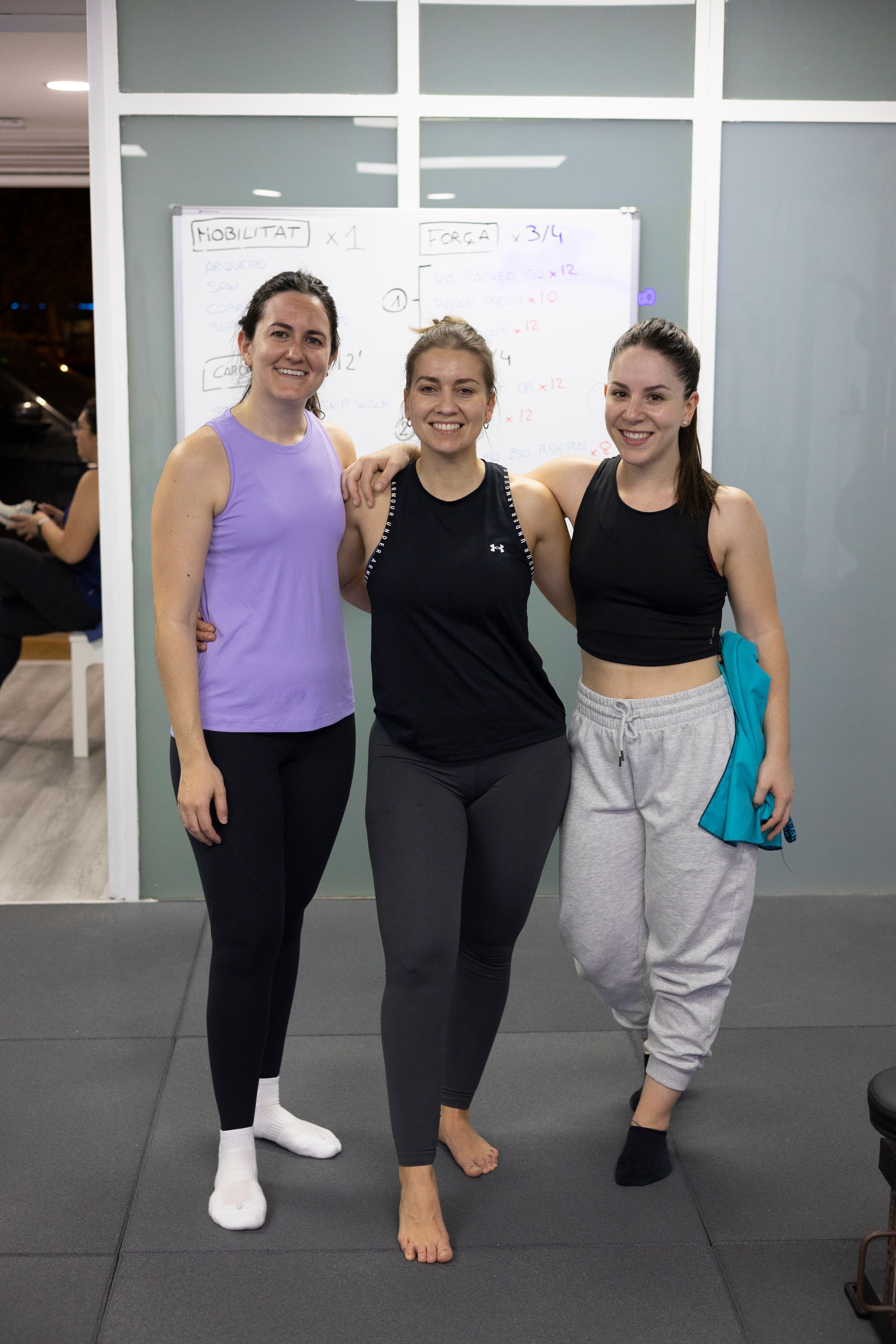 Tres mujeres posan para una foto en un gimnasio.