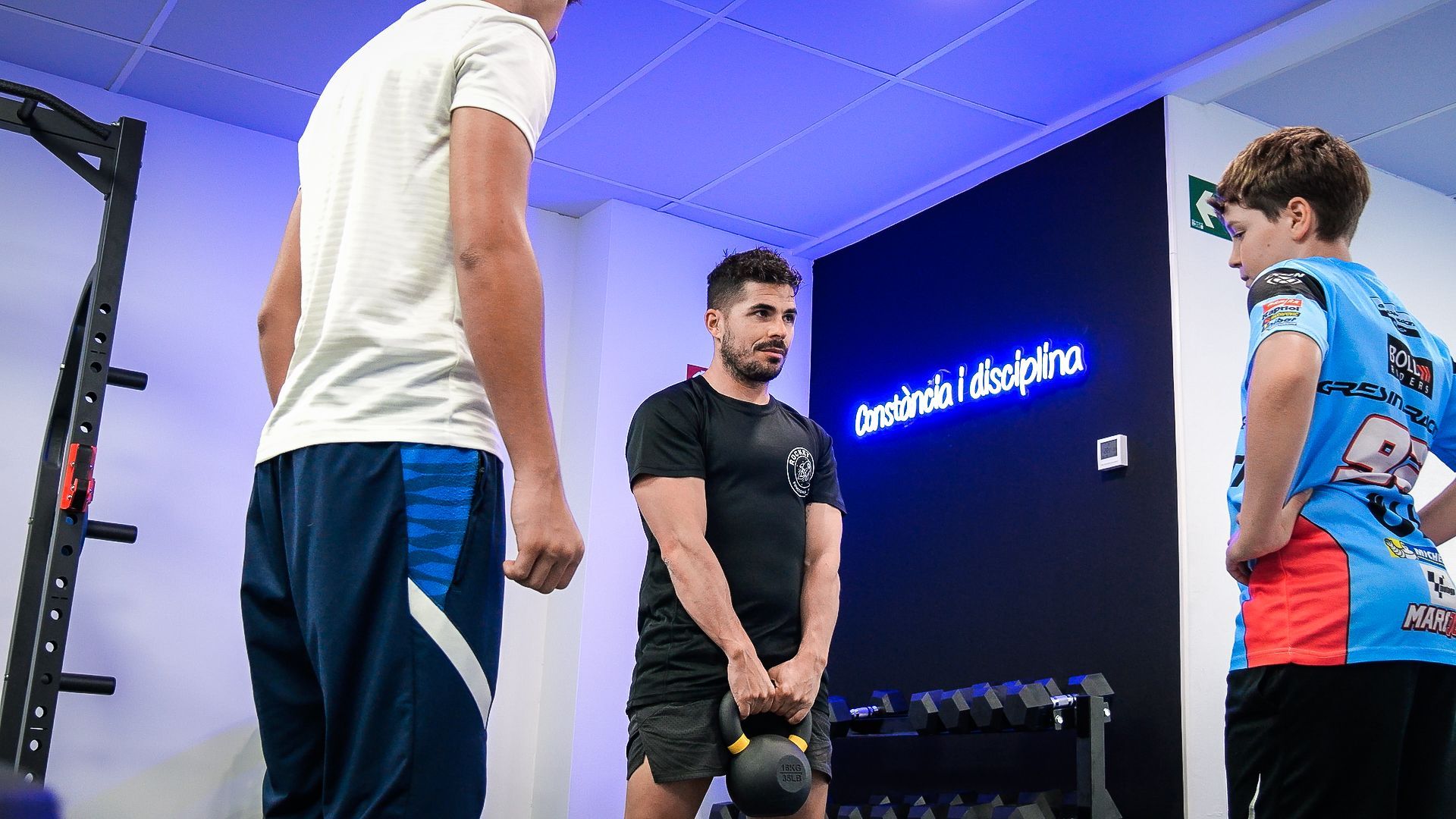 Un grupo de hombres están de pie en un gimnasio hablando entre ellos.