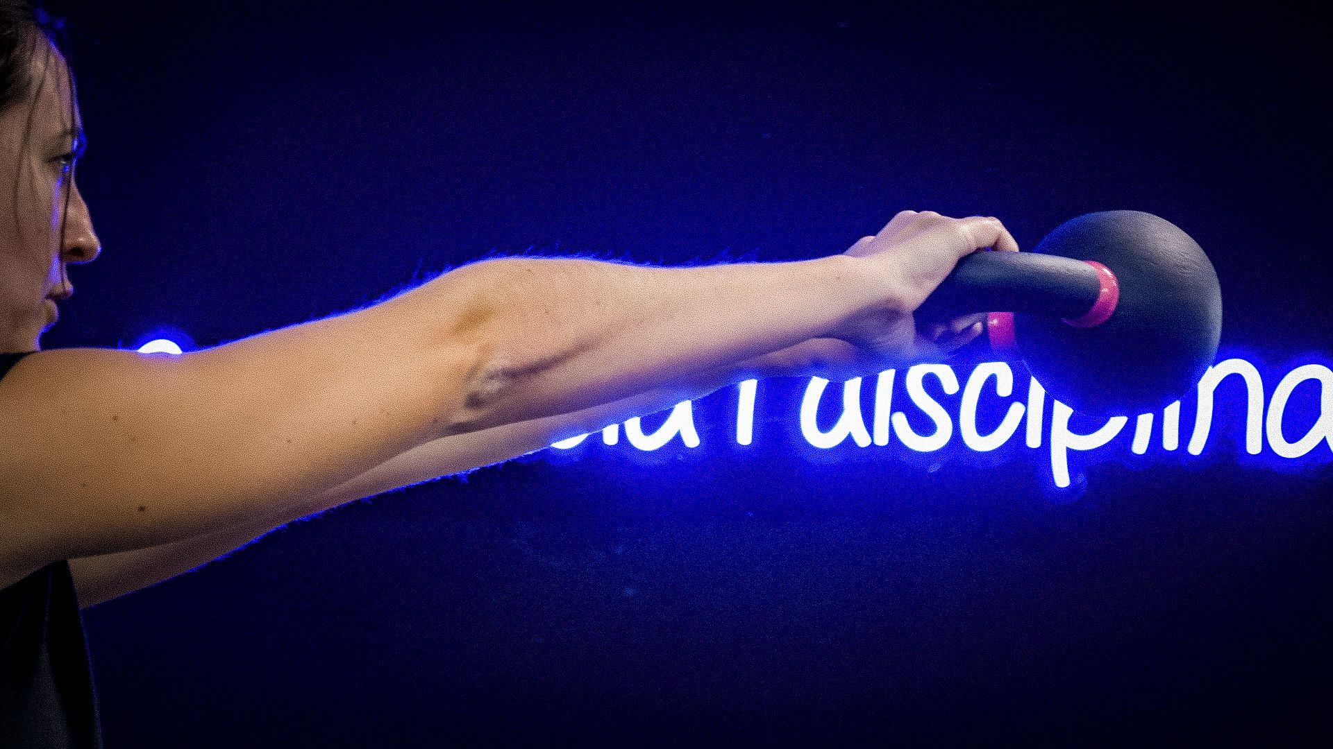Una mujer levanta una pesa rusa frente a un cartel que dice USC.