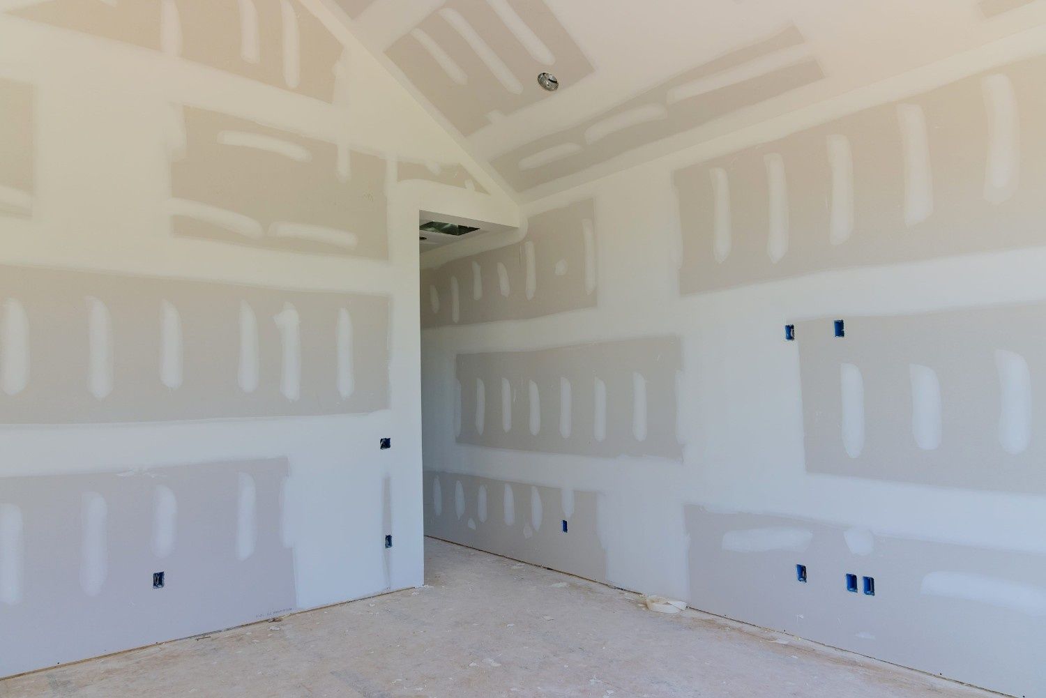 Habitación con paredes de pladur sin terminar, con juntas selladas con cinta adhesiva, paredes al descubierto y tomas de corriente de la construcción.