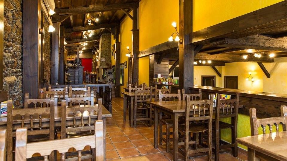 Un restaurante con mesas y sillas de madera y una pared amarilla.