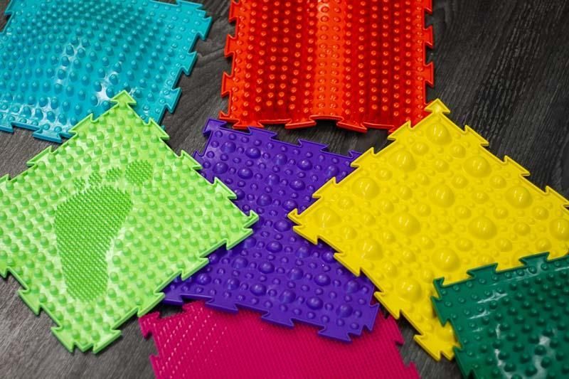 Ein Stapel bunter Matten liegt auf einem Holztisch.