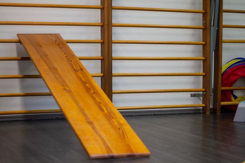 In einer Turnhalle steht eine Holzrutsche auf dem Boden.