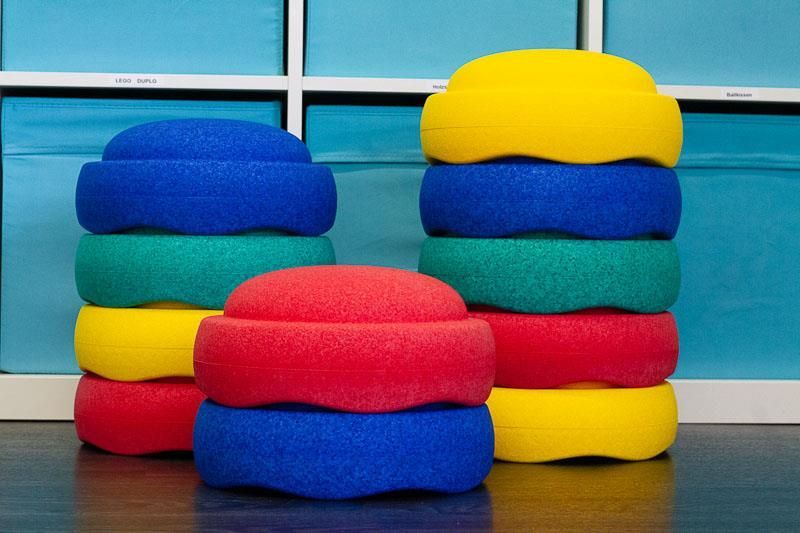 Ein Haufen bunter Kissen ist auf einem Holzboden übereinander gestapelt.