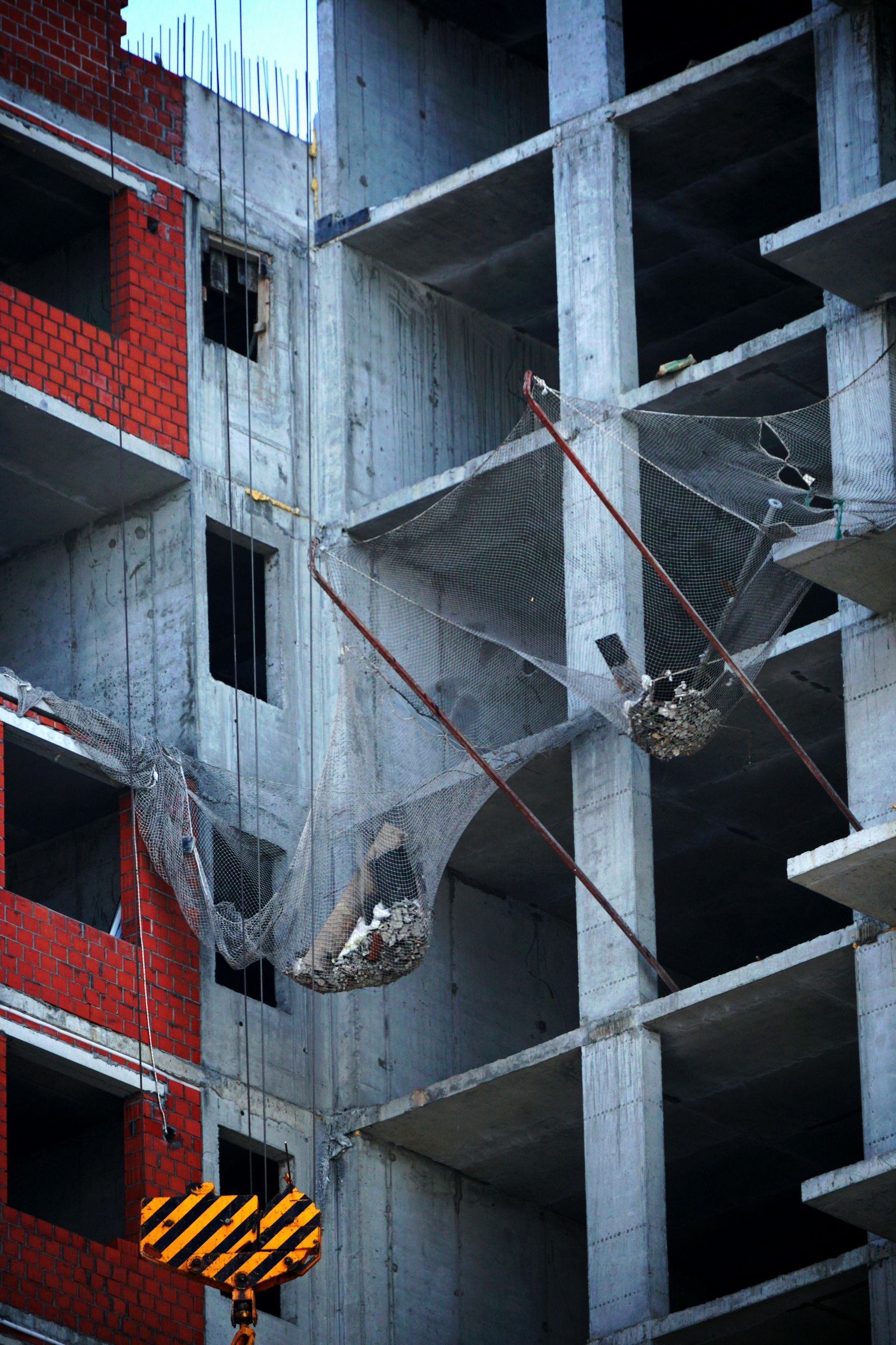 Un bâtiment est en cours de construction avec une grue et un filet de sécurité.