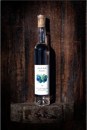 Une bouteille de liqueur de prune est posée sur un tonneau en bois.