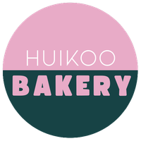 Huikoo Bakeryn logo vaaleanpunaisena ja tummanvihreänä ympyrän sisällä