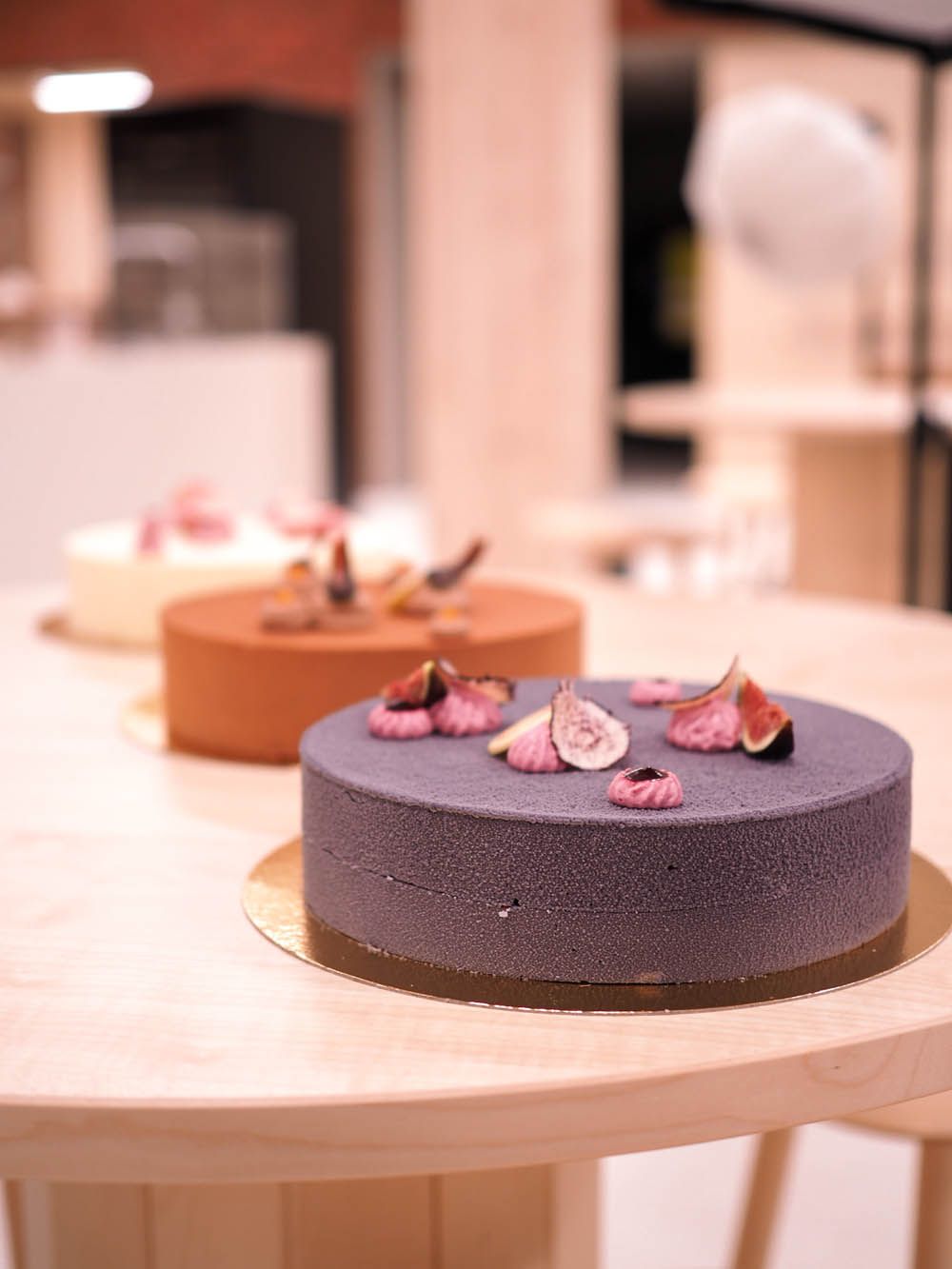 Kaksi pyöreää, kuorrutettua kakkua viikunatäytteillä puupöydällä leipomossa