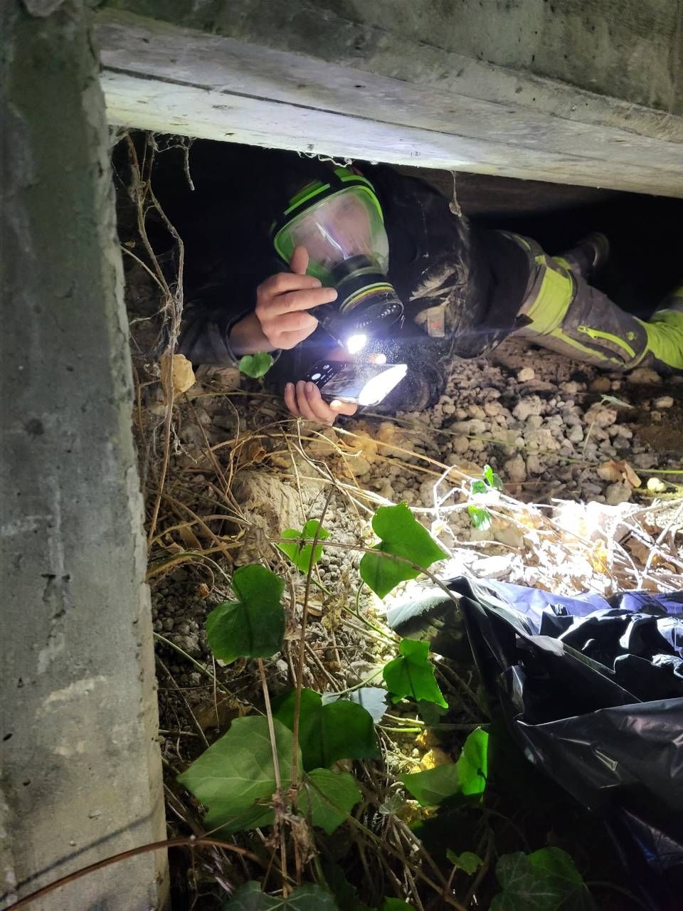 Un homme portant un masque à gaz tient une lampe de poche dans un tunnel.