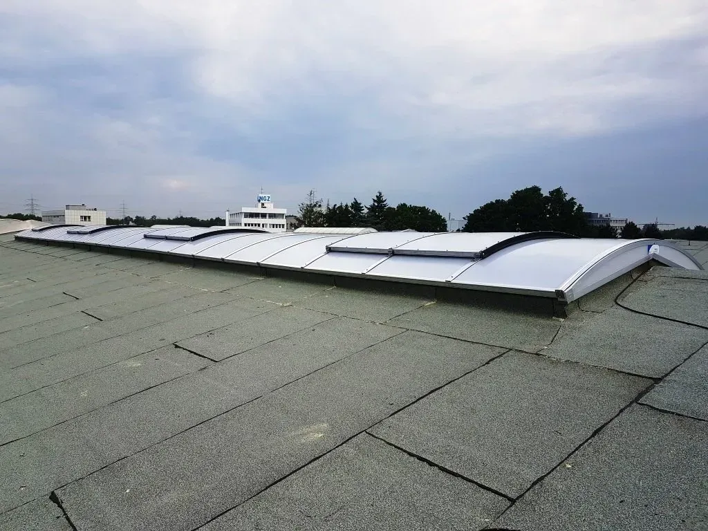 Solarpaneele auf einem grauen Schindeldach unter bewölktem Himmel.