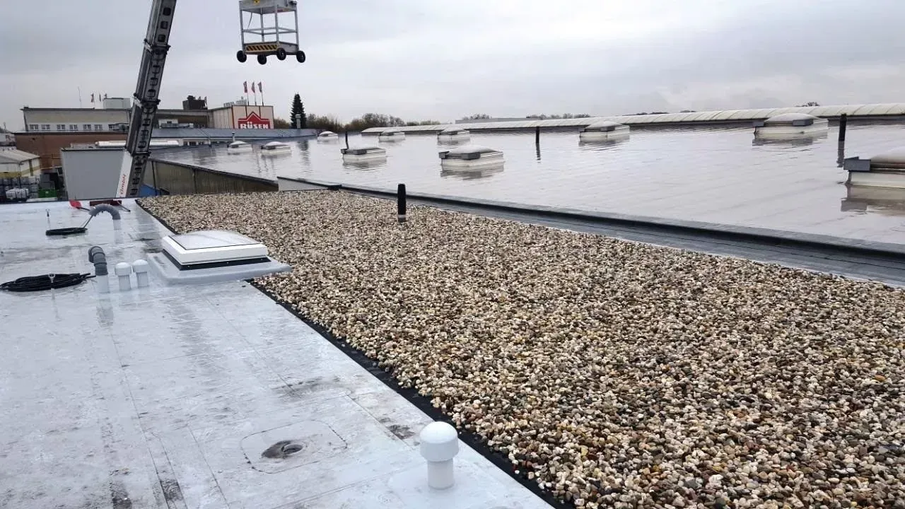 Ein schneebedeckter Steg an einem felsigen Ufer mit Wasser, vertäuten Booten und einem Sessellift darüber.