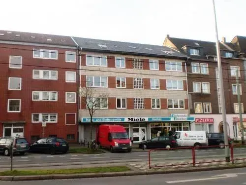 Eine Reihe von Ladenwohnungen mit geparkten Lieferwagen und Autos entlang einer Stadtstraße