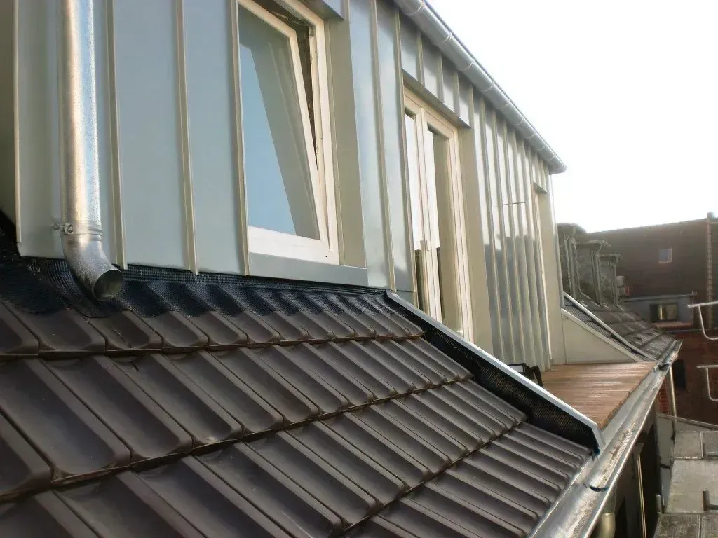 Dachterrasse mit braunem Ziegeldach und weißer Hausverkleidung unter einem bewölkten Himmel