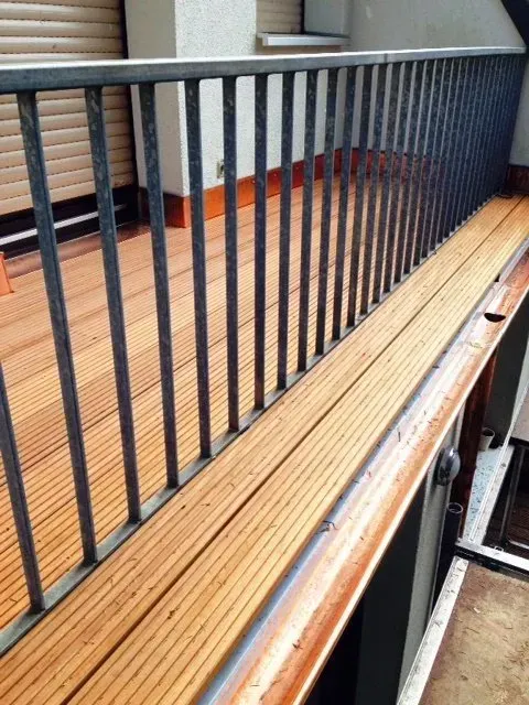 Holzbänke neben schwarzen Metallgeländern in einer Halle mit orangefarbenem Boden
