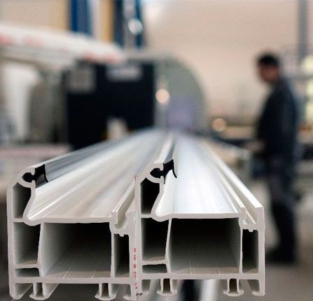 Un primer plano de una viga de aluminio blanca con un hombre al fondo.