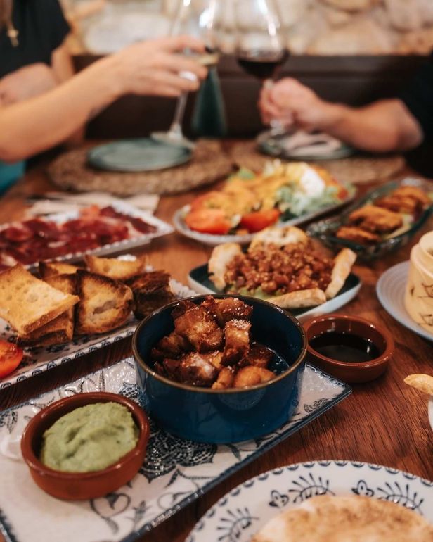Mesa compartida con una variedad de tapas y bebidas en un ambiente de restaurante acogedor.