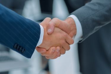 Zwei Männer in Anzügen geben sich die Hand